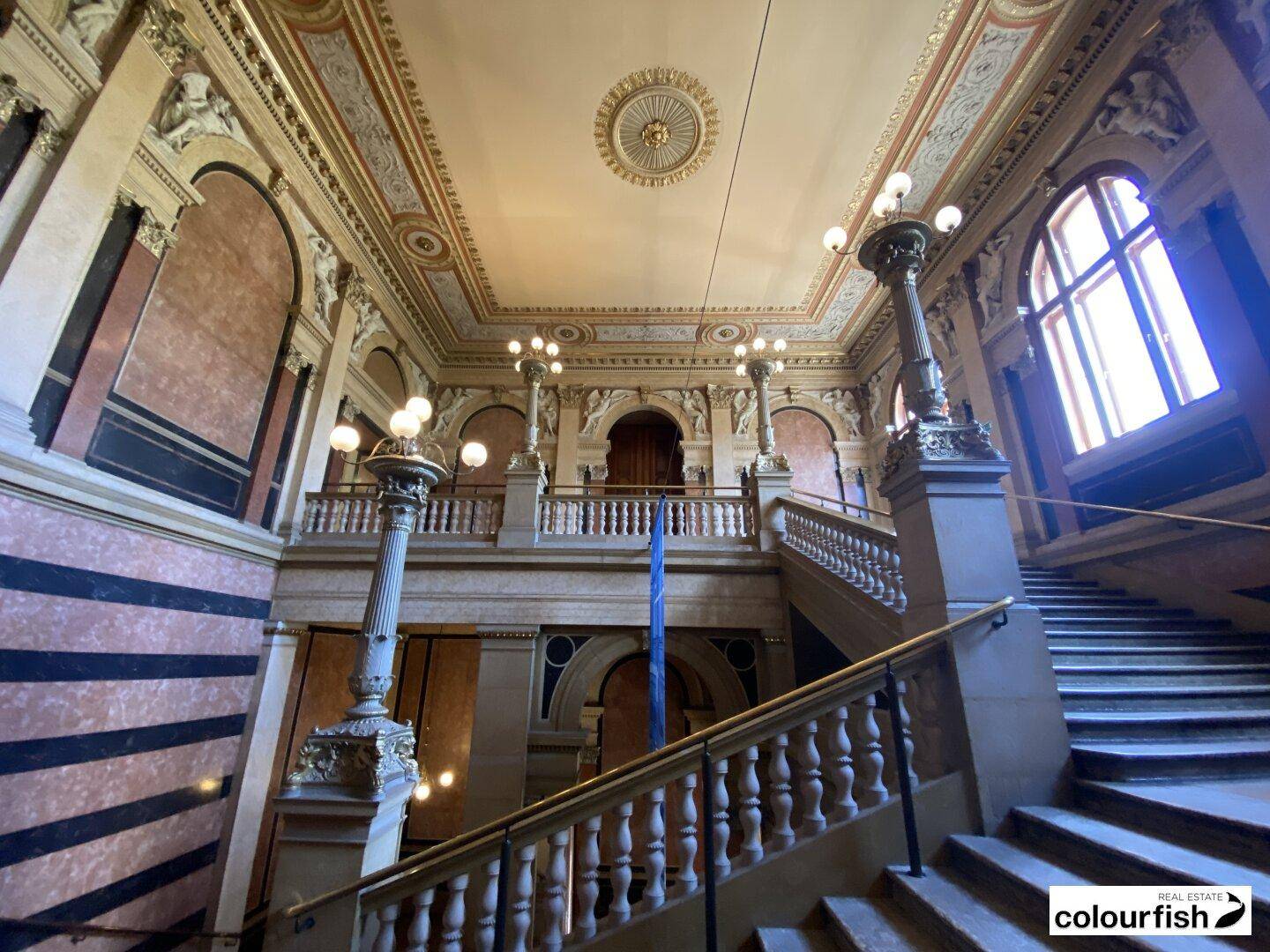 Prächtiges Treppenhaus mit aufwendigen Verzierungen, hohen Decken und großen Fenstern, das eine luxuriöse Atmosphäre schafft.