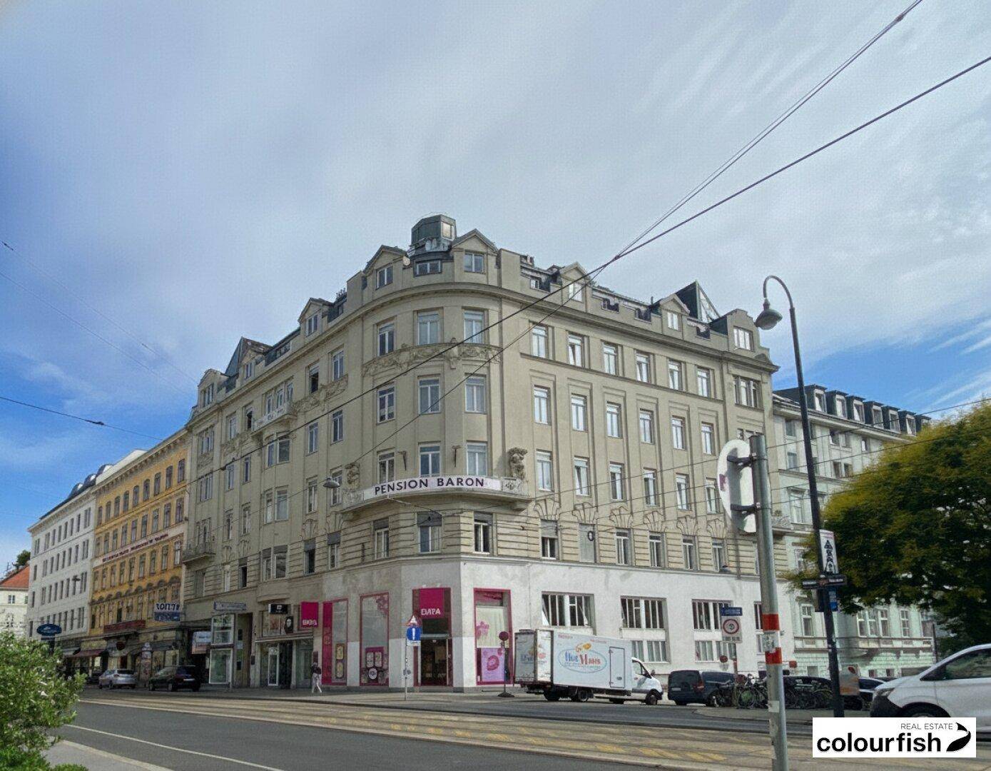 Ansicht des historischen Gebäudes von der Straße aus, umgeben von weiteren Stadtgebäuden.