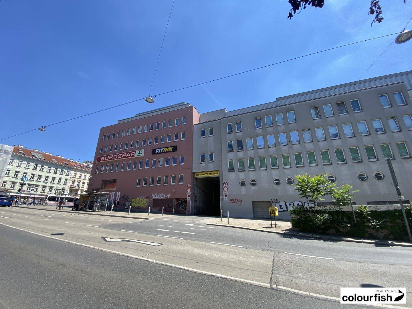 Straßenansicht eines modernen Geschäftsgebäudes mit verschiedenen Geschäften und Büros.