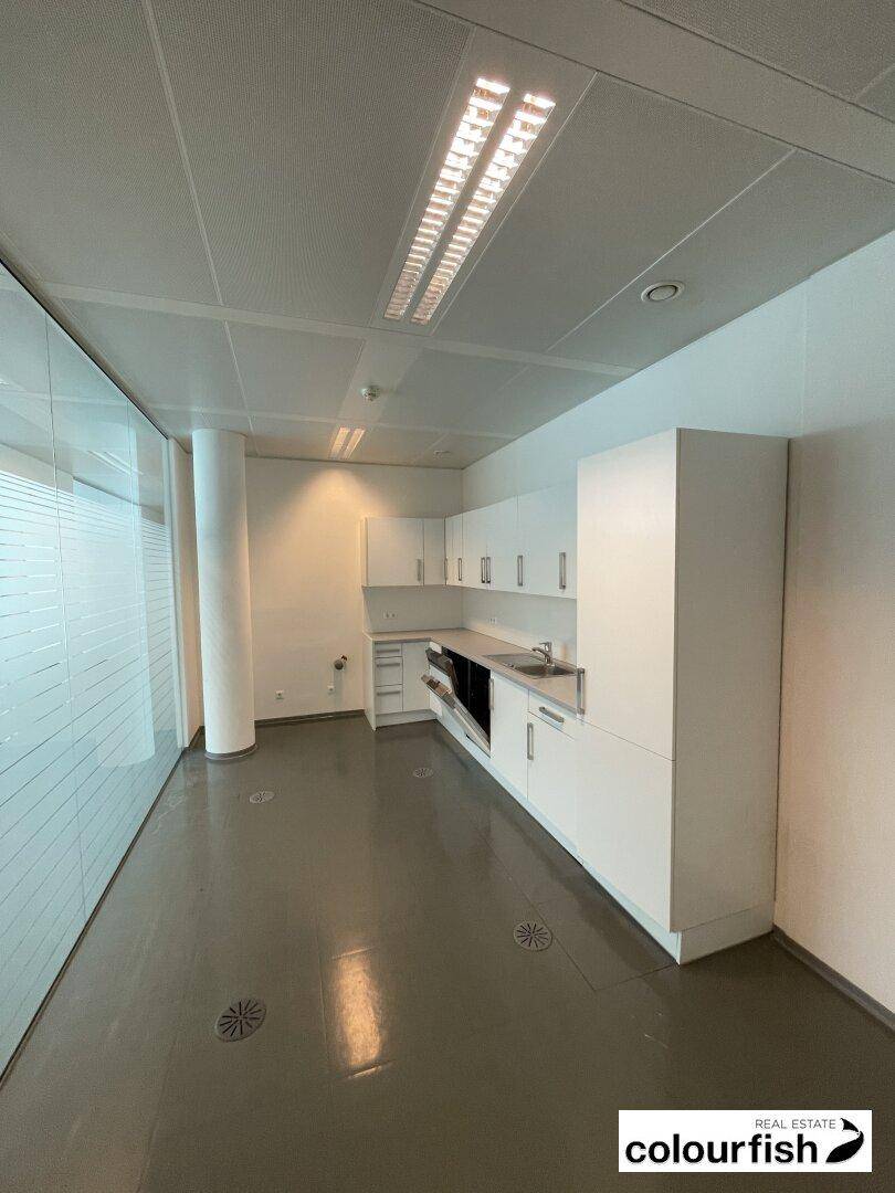 Funktionale Teeküche mit weißen Schränken und Spüle, ideal für Pausen im Büroalltag.