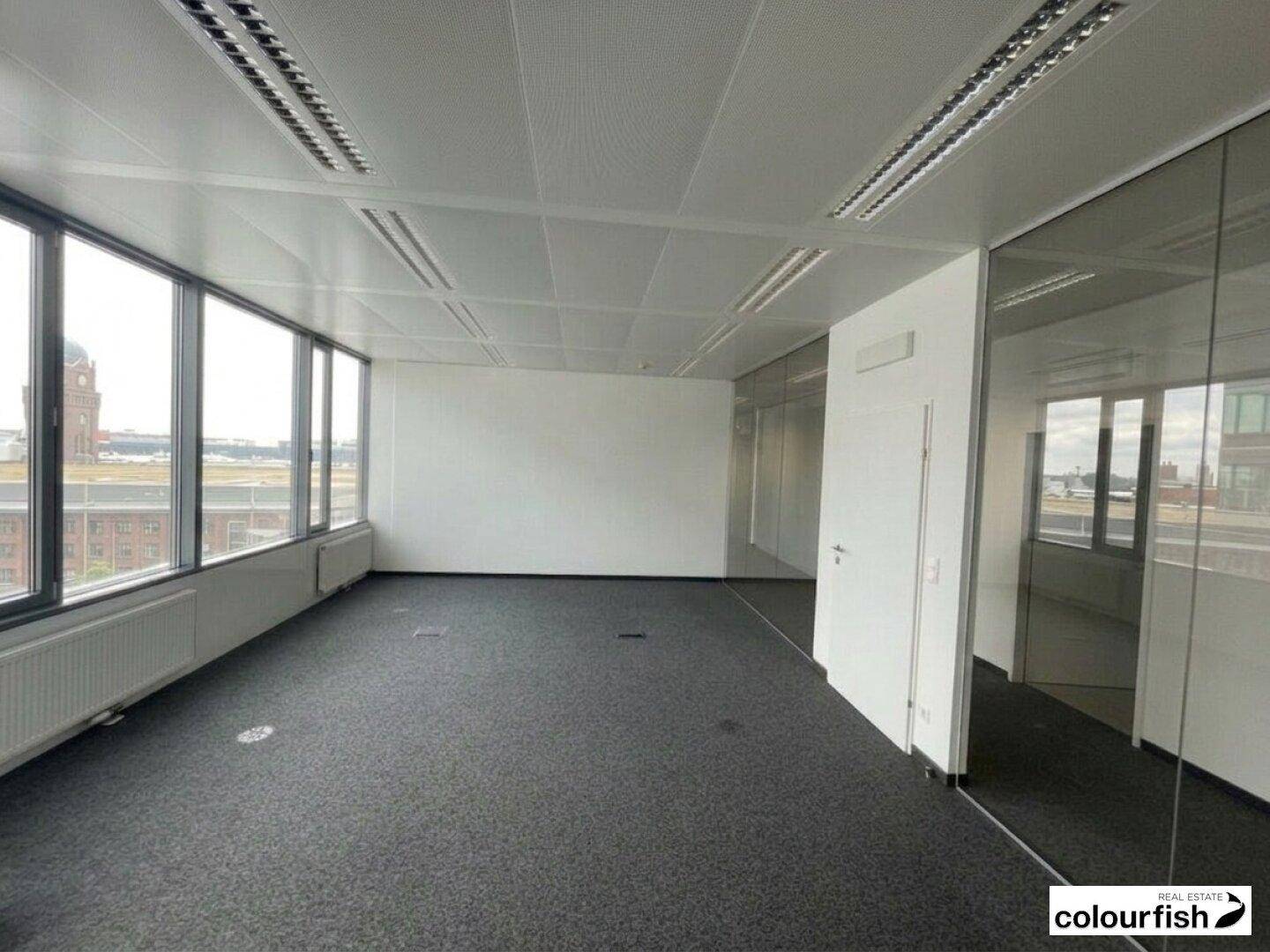 Großes Eckbüro mit weitem Ausblick durch die Fensterfront und modernen Glaswänden.
