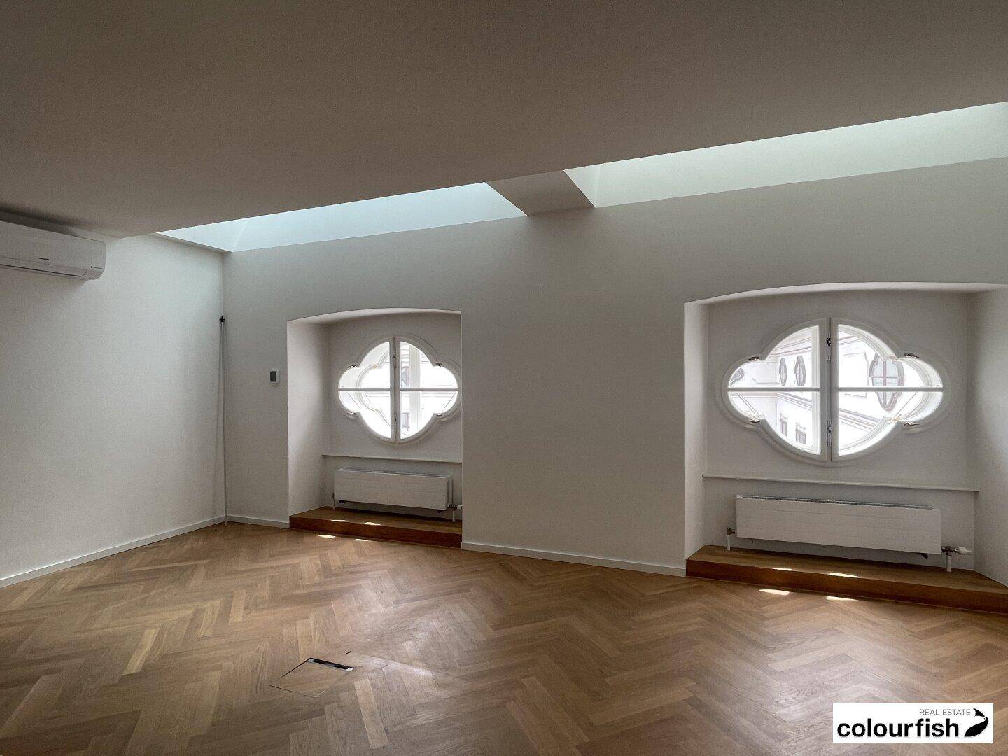 Geräumiger Raum mit zwei markanten kleeblattförmigen Fenstern und Oberlichtern, die für viel Helligkeit sorgen.