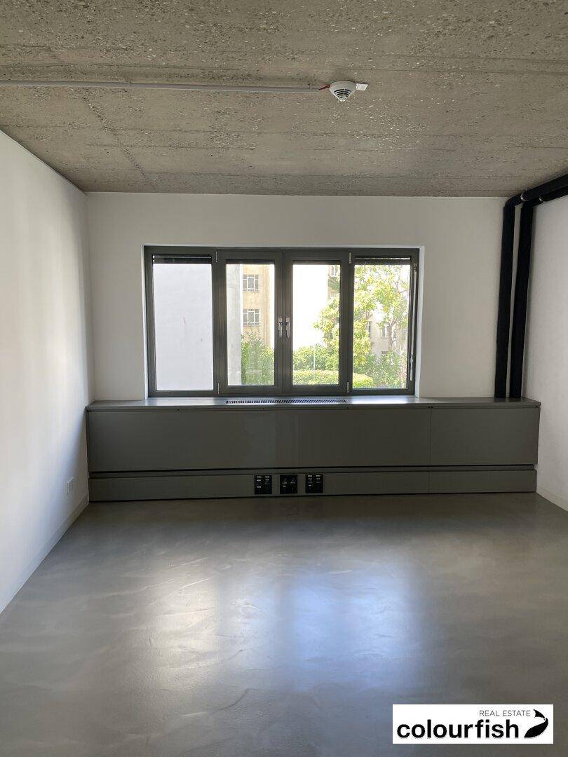 Kleineres Büro mit Fenster und Blick ins Grüne, ausgestattet mit funktionalen Elementen.