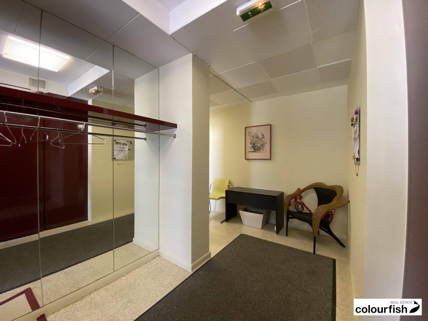 Heller Empfangsbereich mit Spiegelfront, Garderobe und Sitzgelegenheiten.