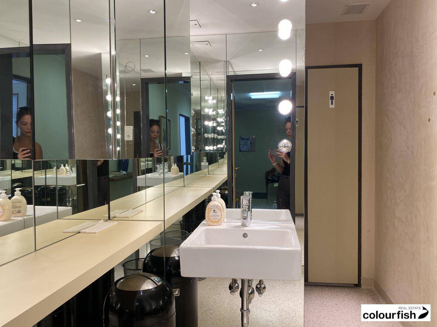 Modernes Badezimmer mit mehreren Spiegeln, Waschbecken und Beleuchtung.