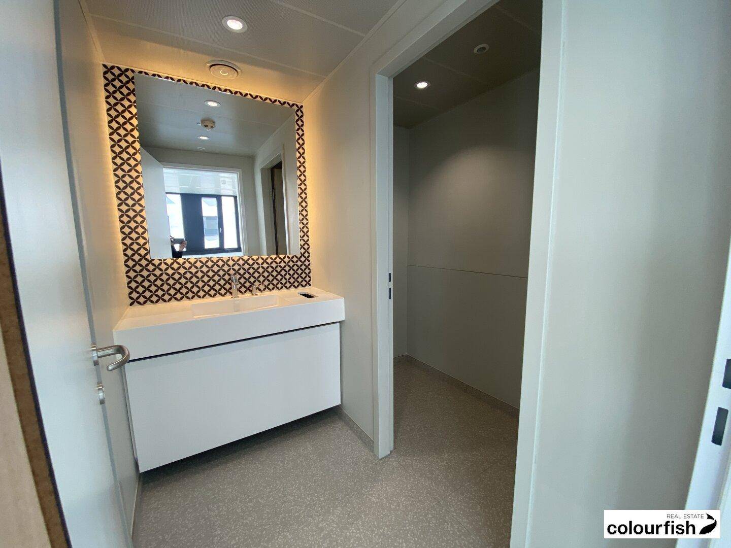 Modernes Badezimmer mit stilvollem Waschtisch, beleuchtetem Spiegel und minimalistischem Design.