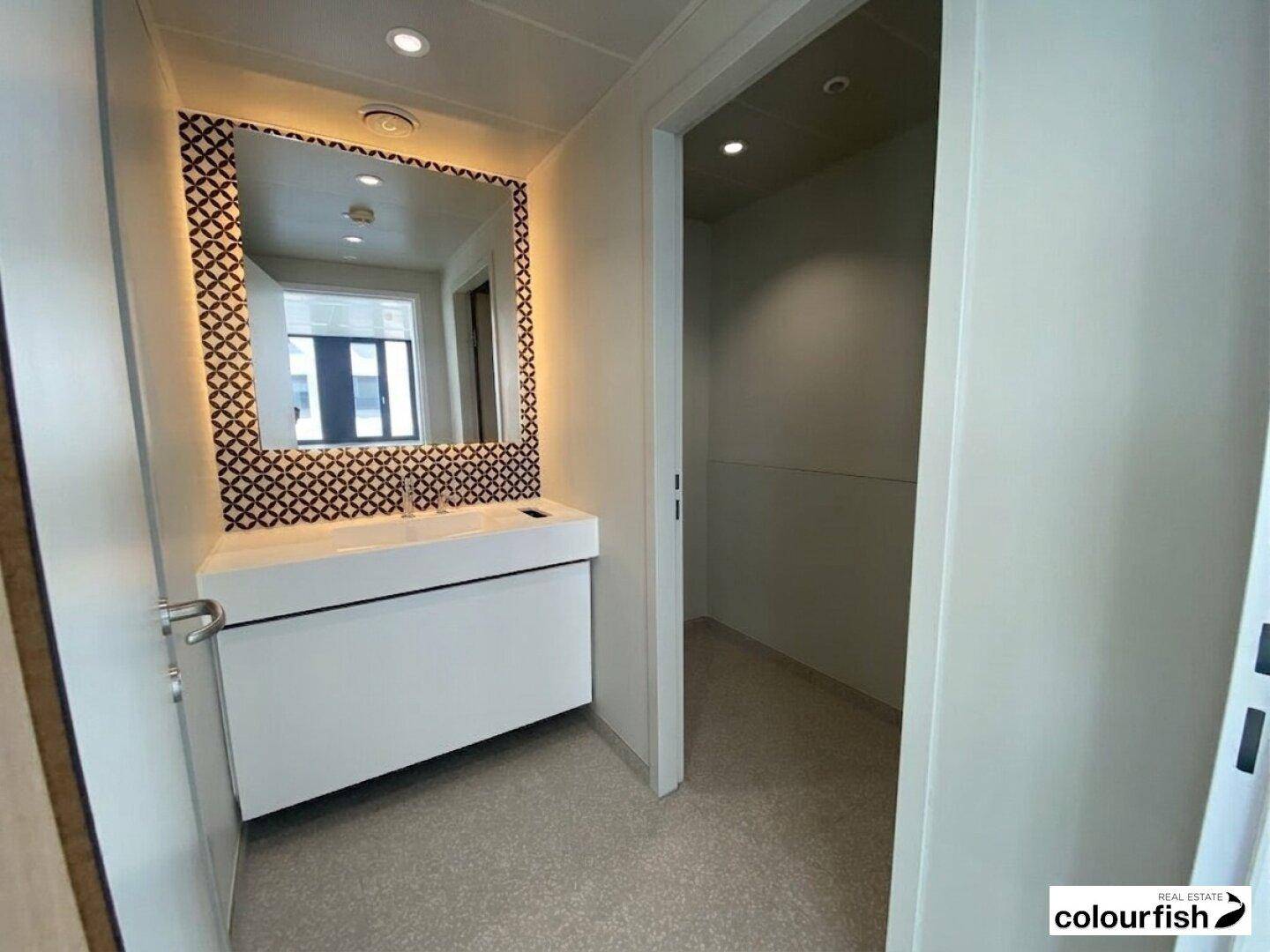 Modernes Badezimmer mit Waschbecken, Spiegel und dekorativen Fliesen an der Wand.