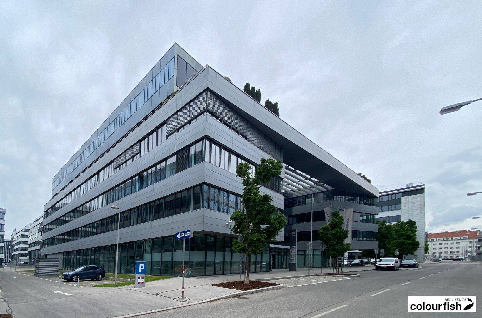 Ansicht eines zeitgenössischen Bürokomplexes mit großen Fenstern und einer klaren architektonischen Linie.