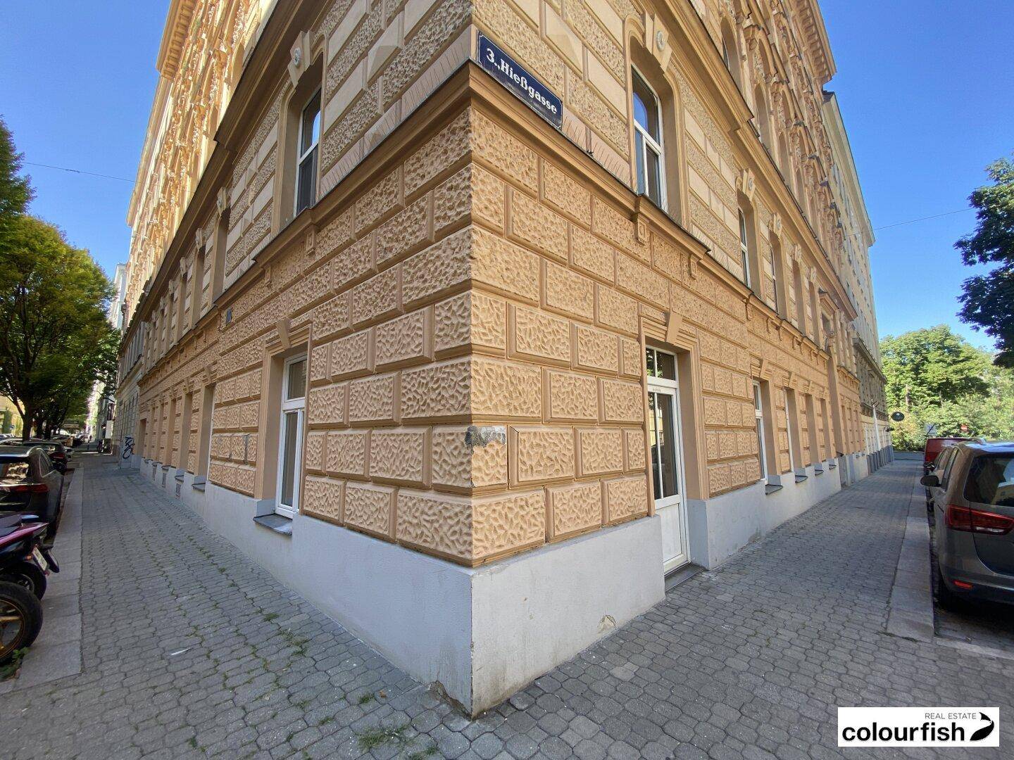 Eckansicht eines historischen Gebäudes mit markanter Fassade und mehreren Eingängen an einer Stadtstraße.