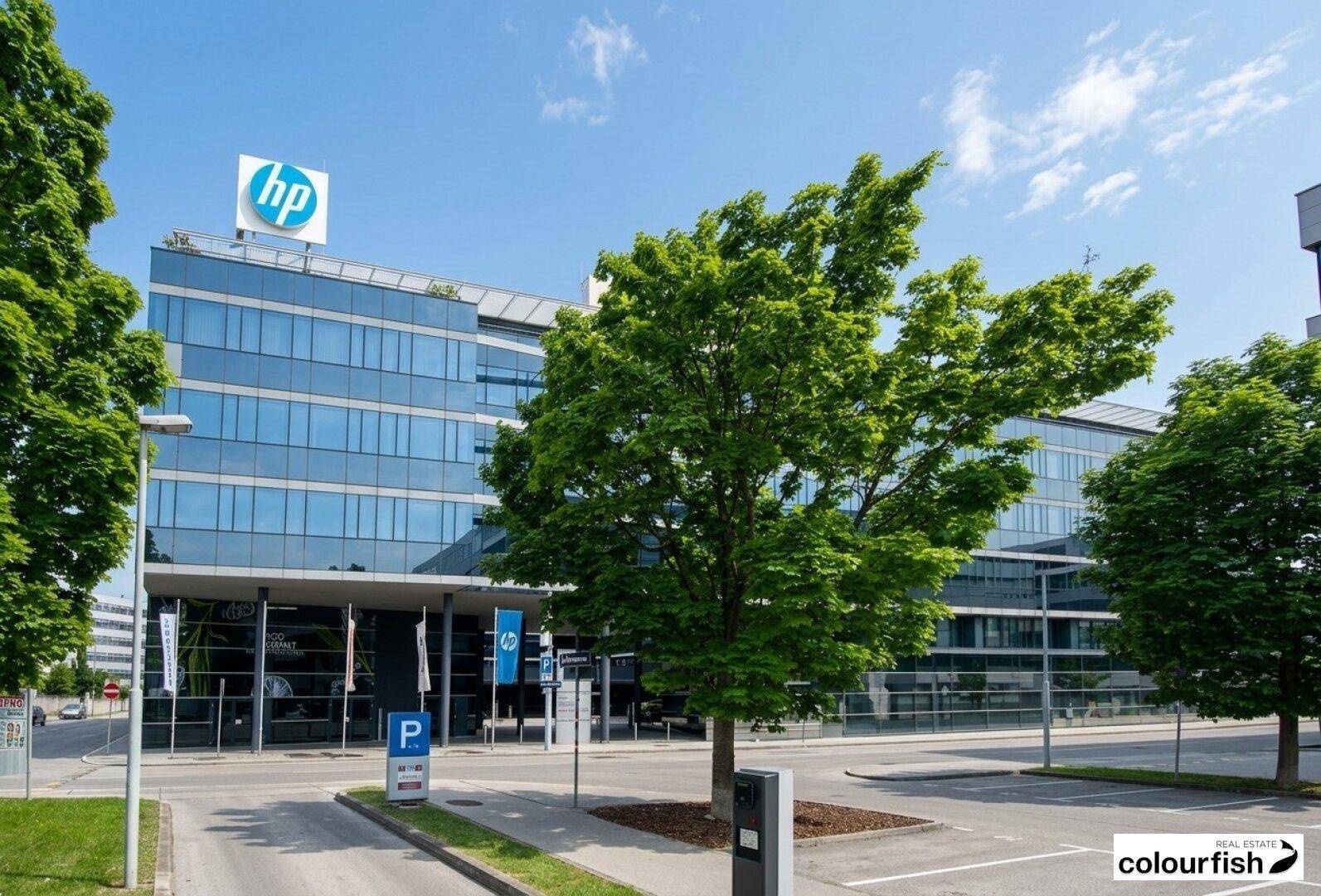 Modernes Bürogebäude mit einer beeindruckenden Glasfassade und dem HP-Logo unter blauem Himmel.