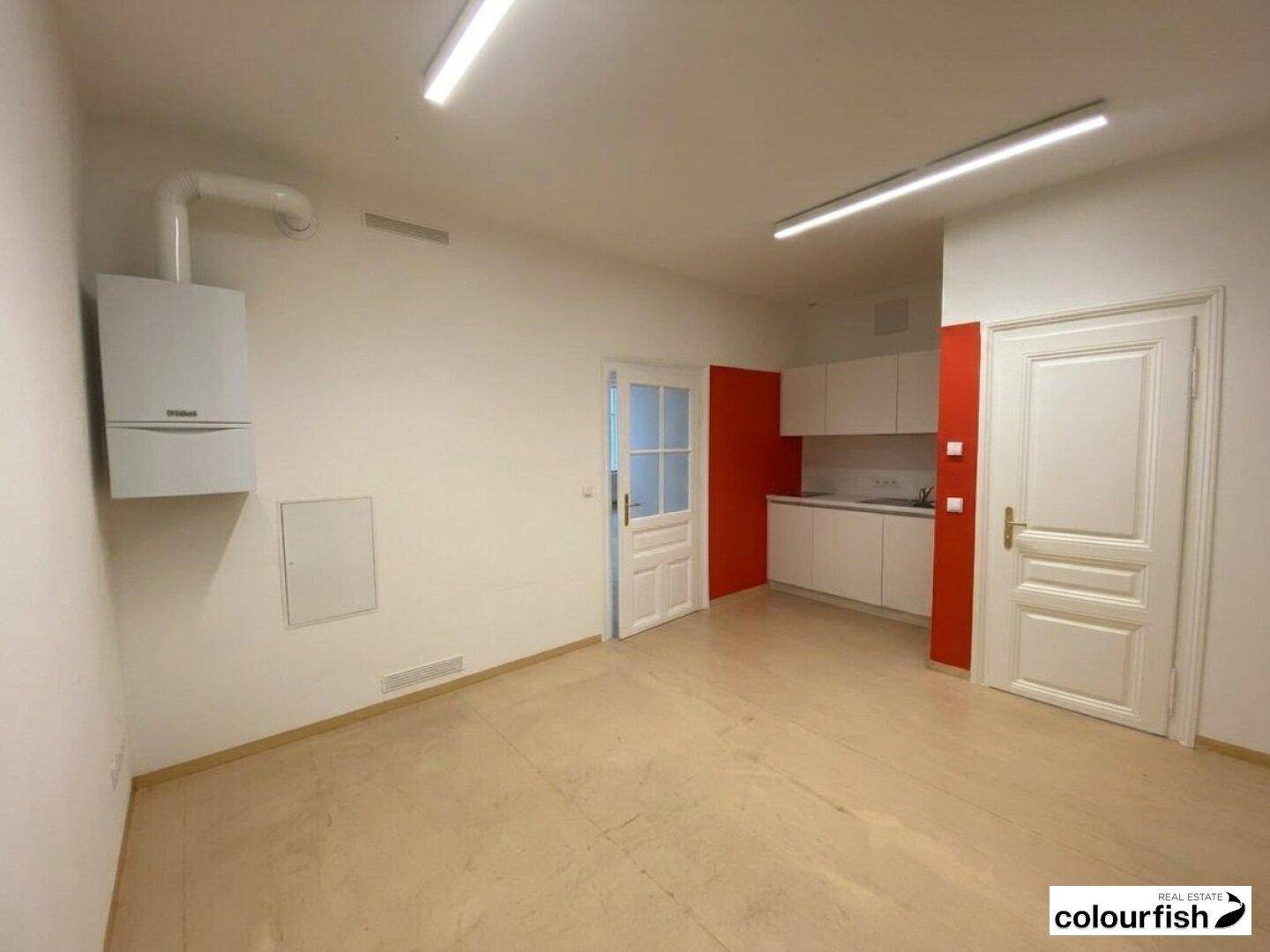 Kleiner Küchenbereich mit weißen Unterschränken, Spüle und Gastherme, ideal für eine Teeküche.