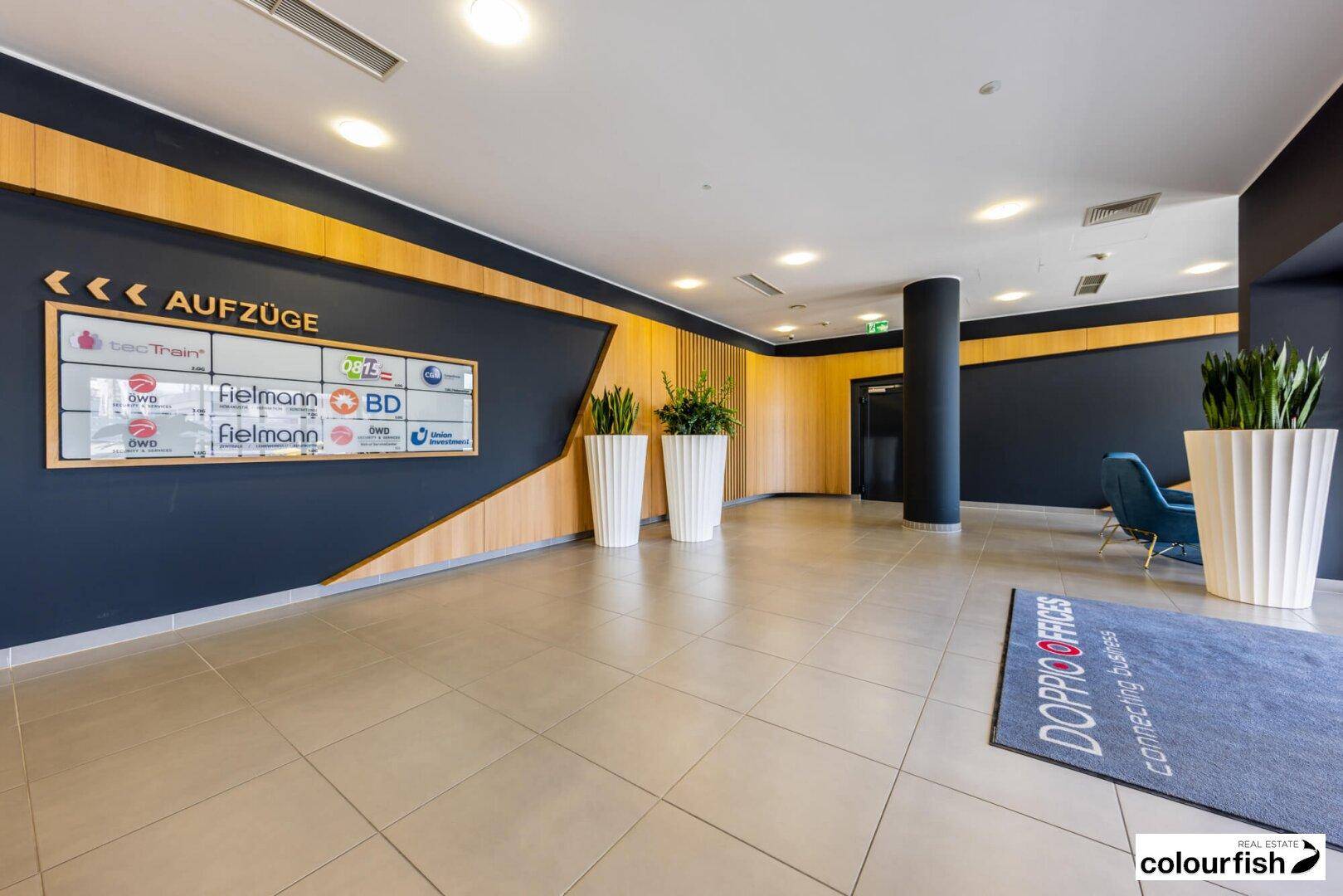 Geräumige Lobby mit modernen Designelementen, Fliesenboden und Sitzgelegenheiten für Besucher.