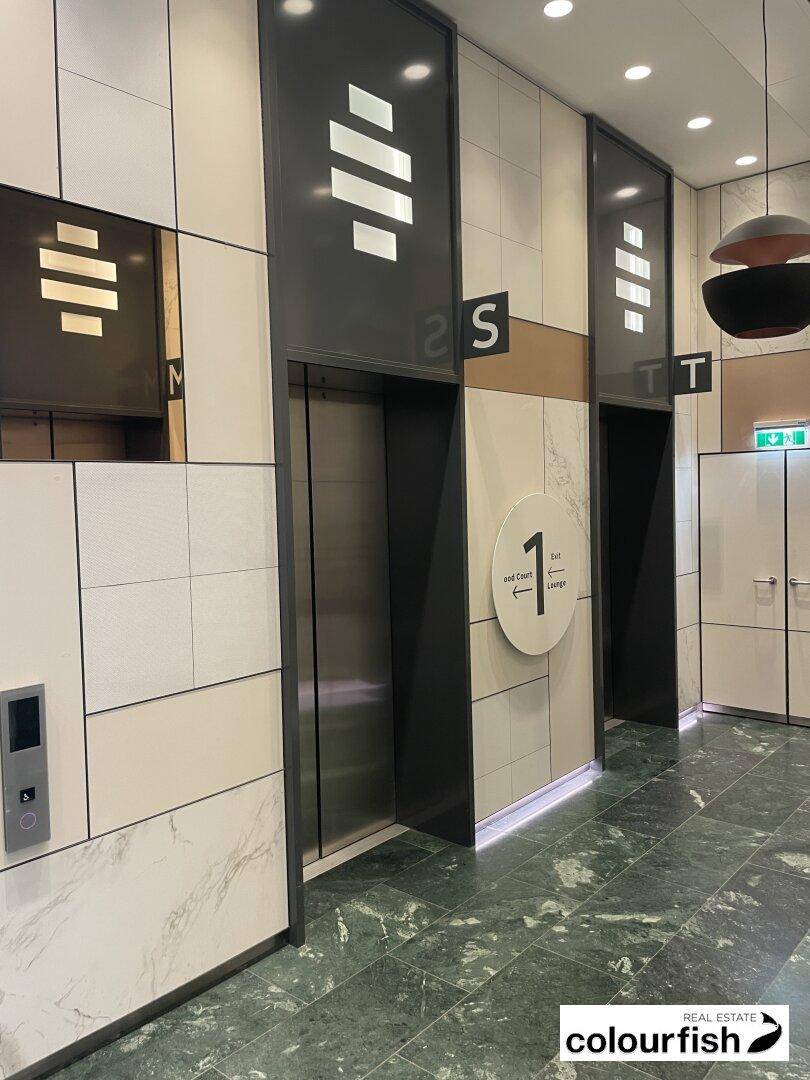 Moderner Aufzugsbereich mit mehreren Liften, eleganten Wandverkleidungen und grünem Fliesenboden.
