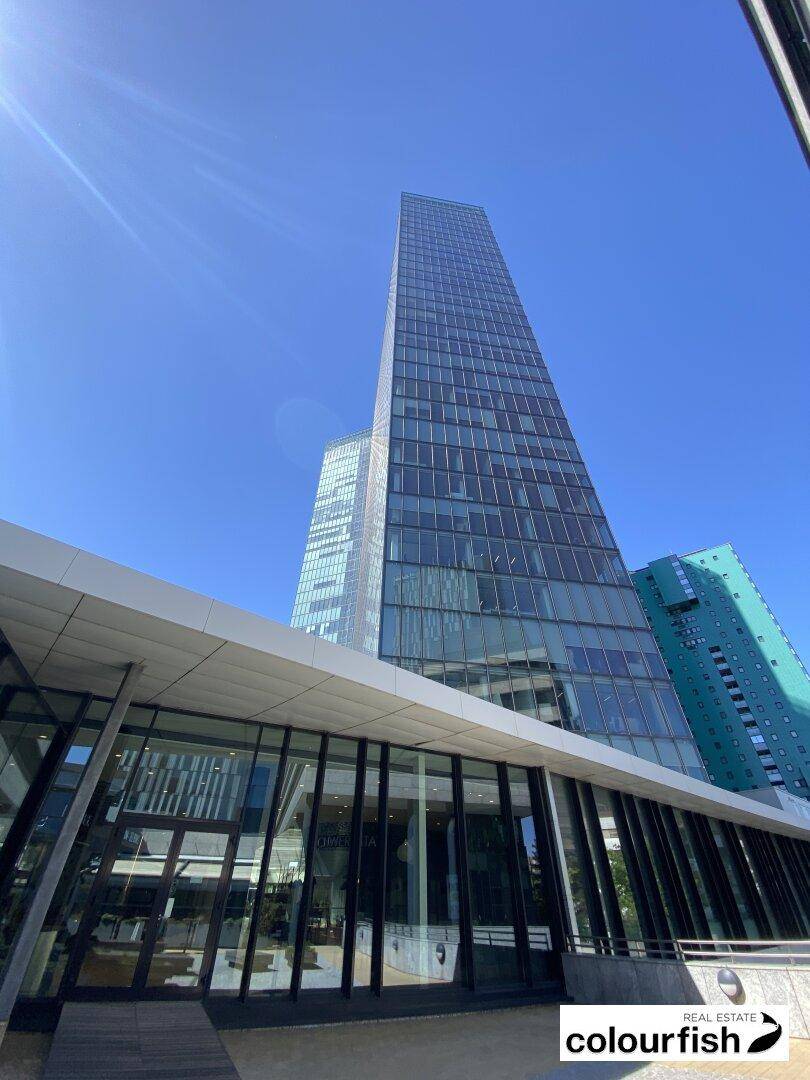 Beeindruckende Glasfassade eines modernen Wolkenkratzers, aufgenommen von der Basis aus an einem sonnigen Tag.