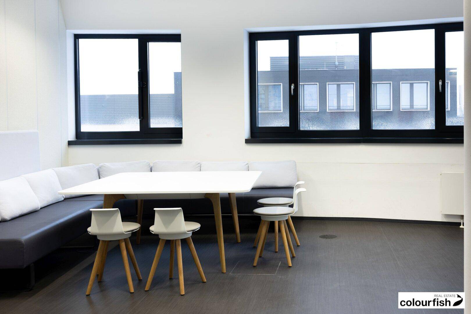 Gemütlicher Loungebereich mit Sitzbank, kleinem Tisch und modernen Hockern, ideal für Pausen.