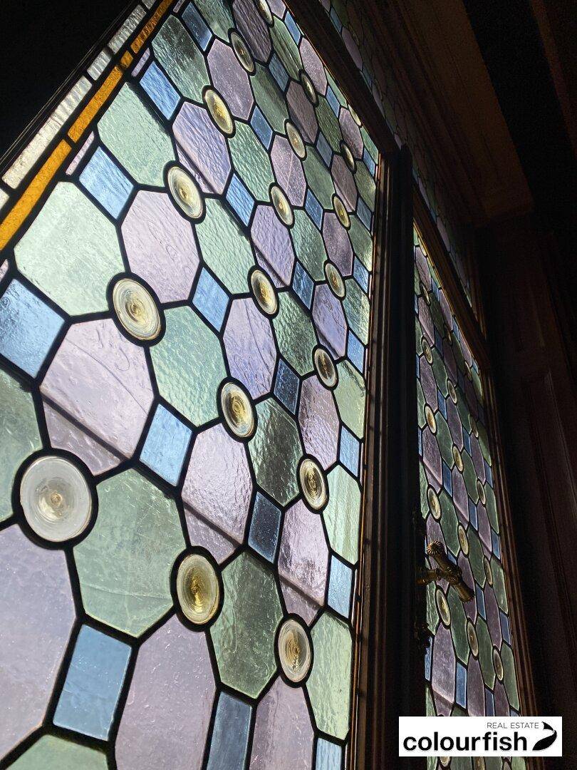 Detailaufnahme eines farbenfrohen Buntglasfensters mit geometrischen Mustern und runden Glaseinsätzen.