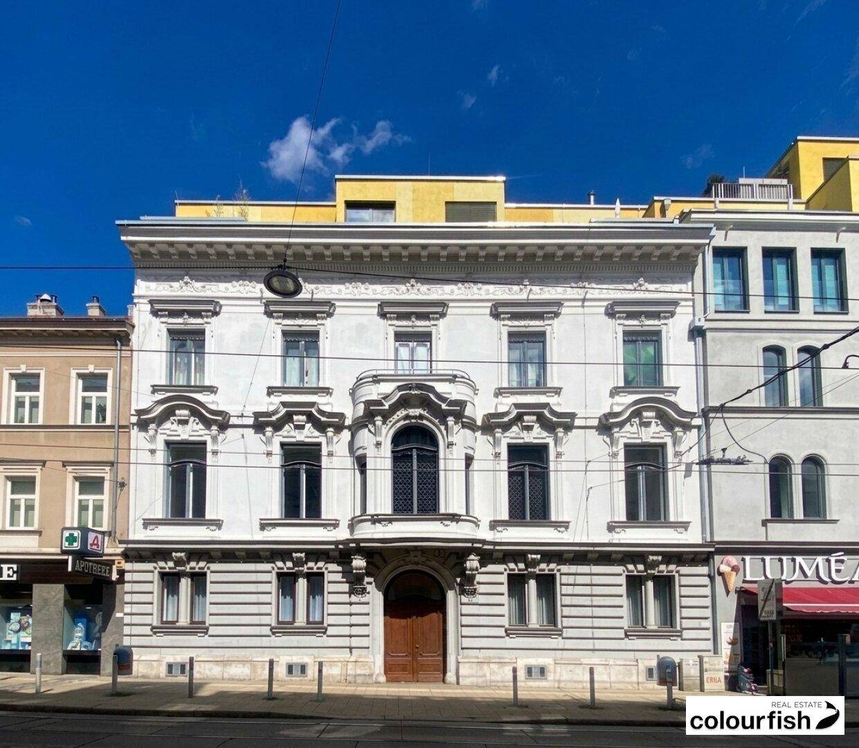 Prächtige historische Fassade eines Gebäudes mit vielen Fenstern und klassischer Architektur an einer Straße.