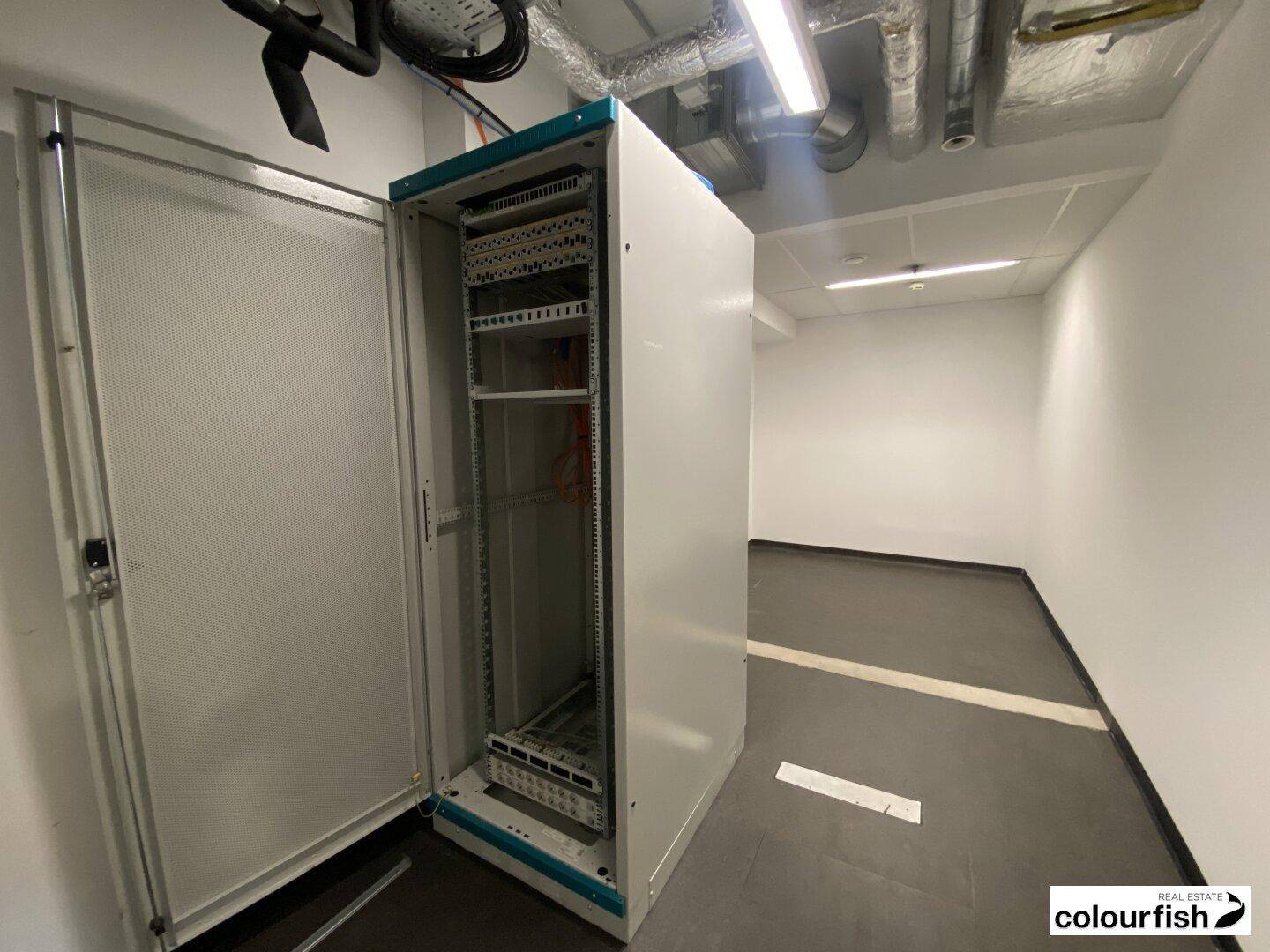 Serverraum mit offenem Serverschrank und sichtbaren Leitungen an der Decke.