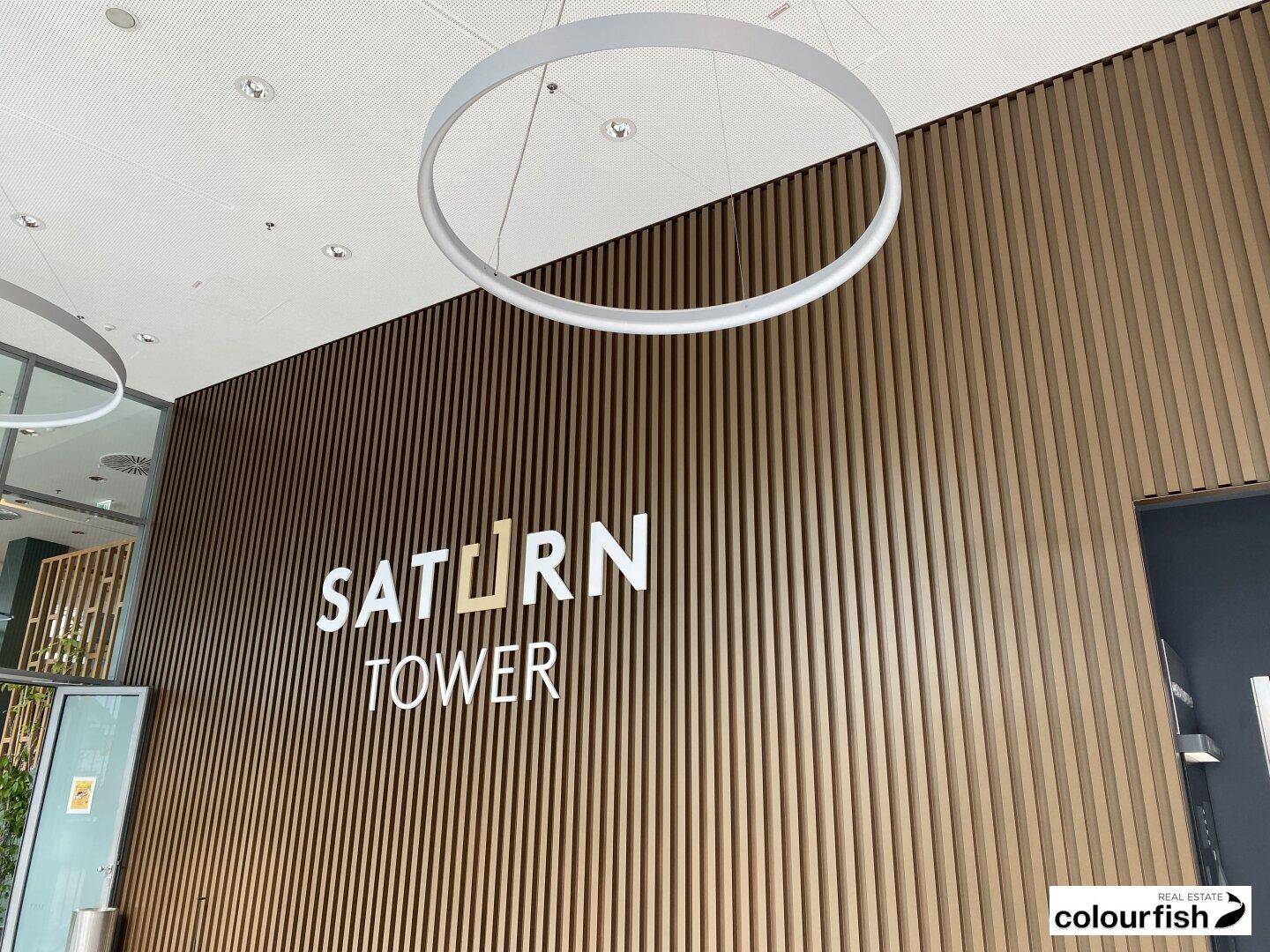 Detailansicht der modernen Lobby mit Holzlamellenwand und dem Schriftzug "Saturn Tower".