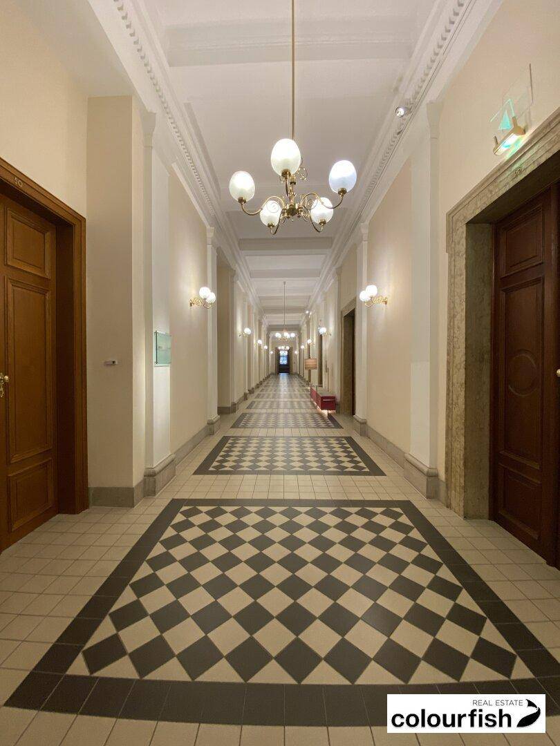Eleganter, langer Flur mit historischen Details, hohen Decken und einem markanten Fliesenbodenmuster.