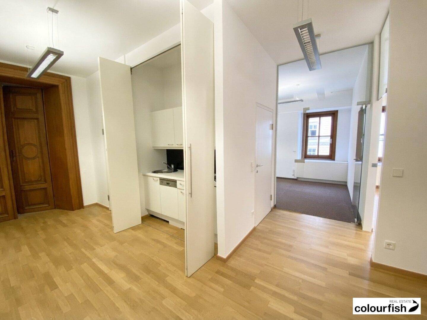 Heller Flur mit Holzboden und einer versteckten Küchenzeile, die sich diskret in den Raum einfügt.