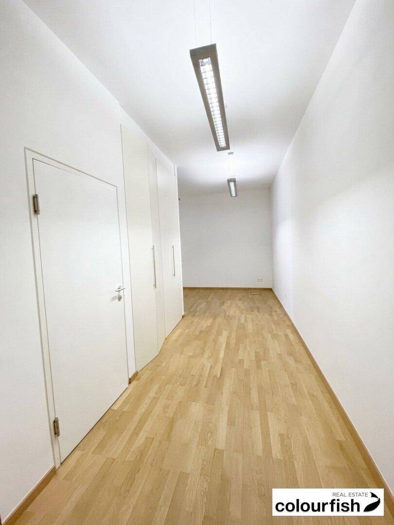 Langer, heller Flur mit Holzboden und praktischen Einbauschränken entlang der Wand.