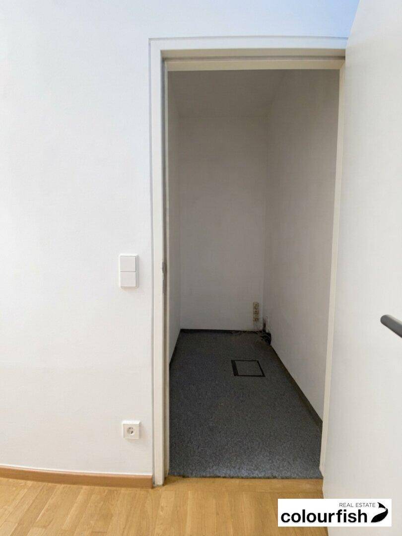 Kleiner Abstellraum mit grauem Teppichboden und weißen Wänden, ideal für zusätzlichen Stauraum.