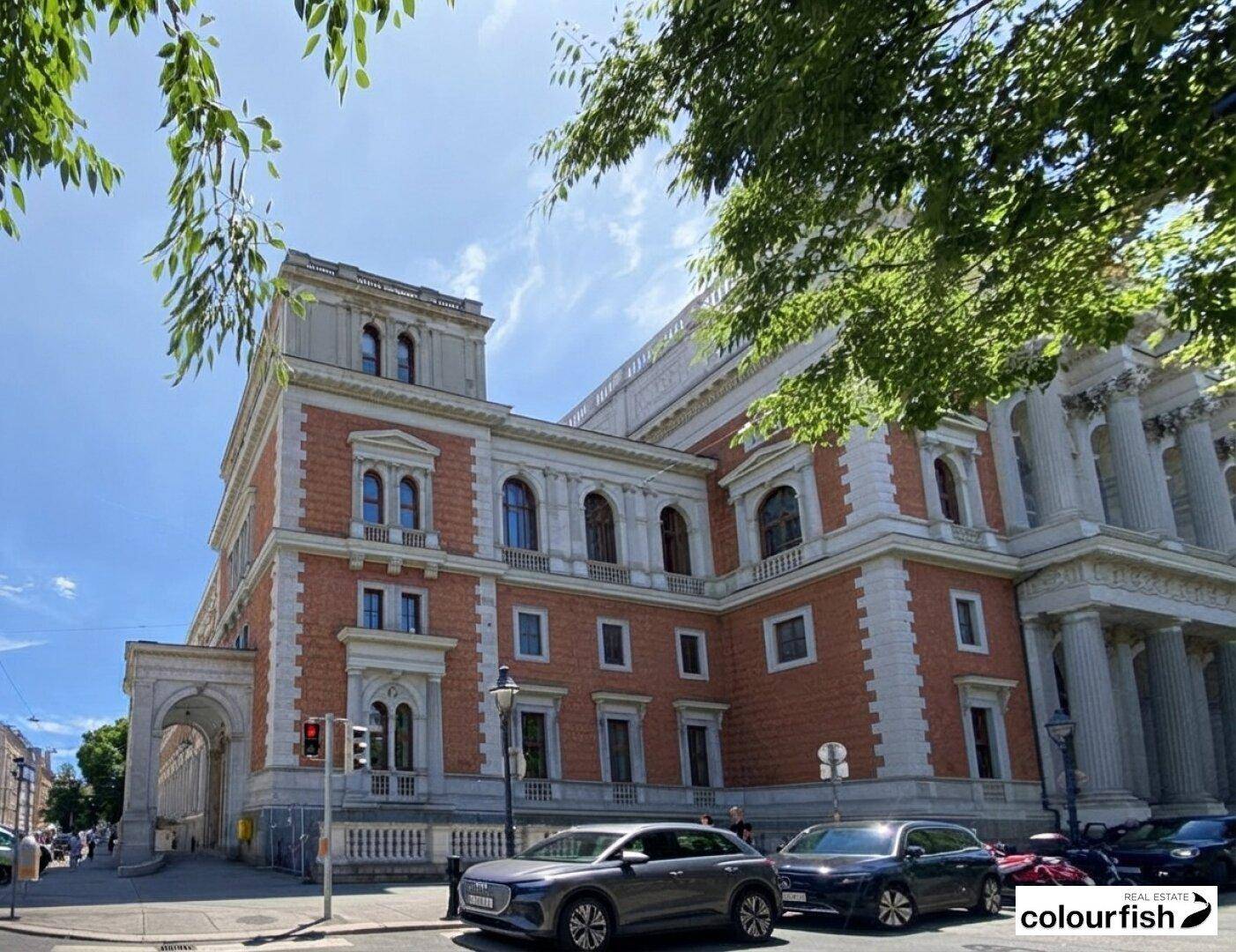 Prächtiges historisches Gebäude mit klassischer Architektur und roter Ziegelfassade an einer belebten Straße.