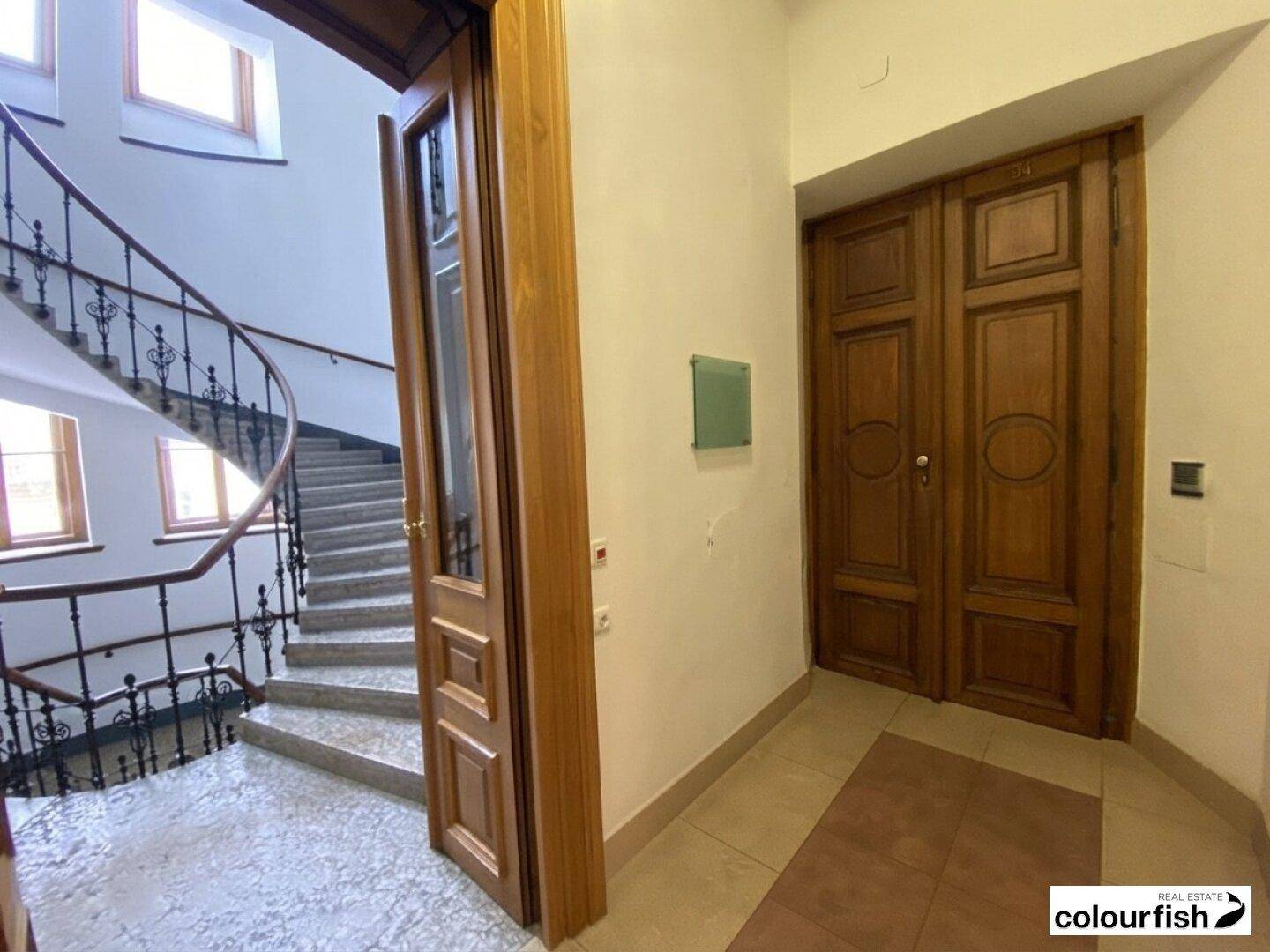 Repräsentativer Eingangsbereich mit einer geschwungenen Treppe und eleganten Holztüren.