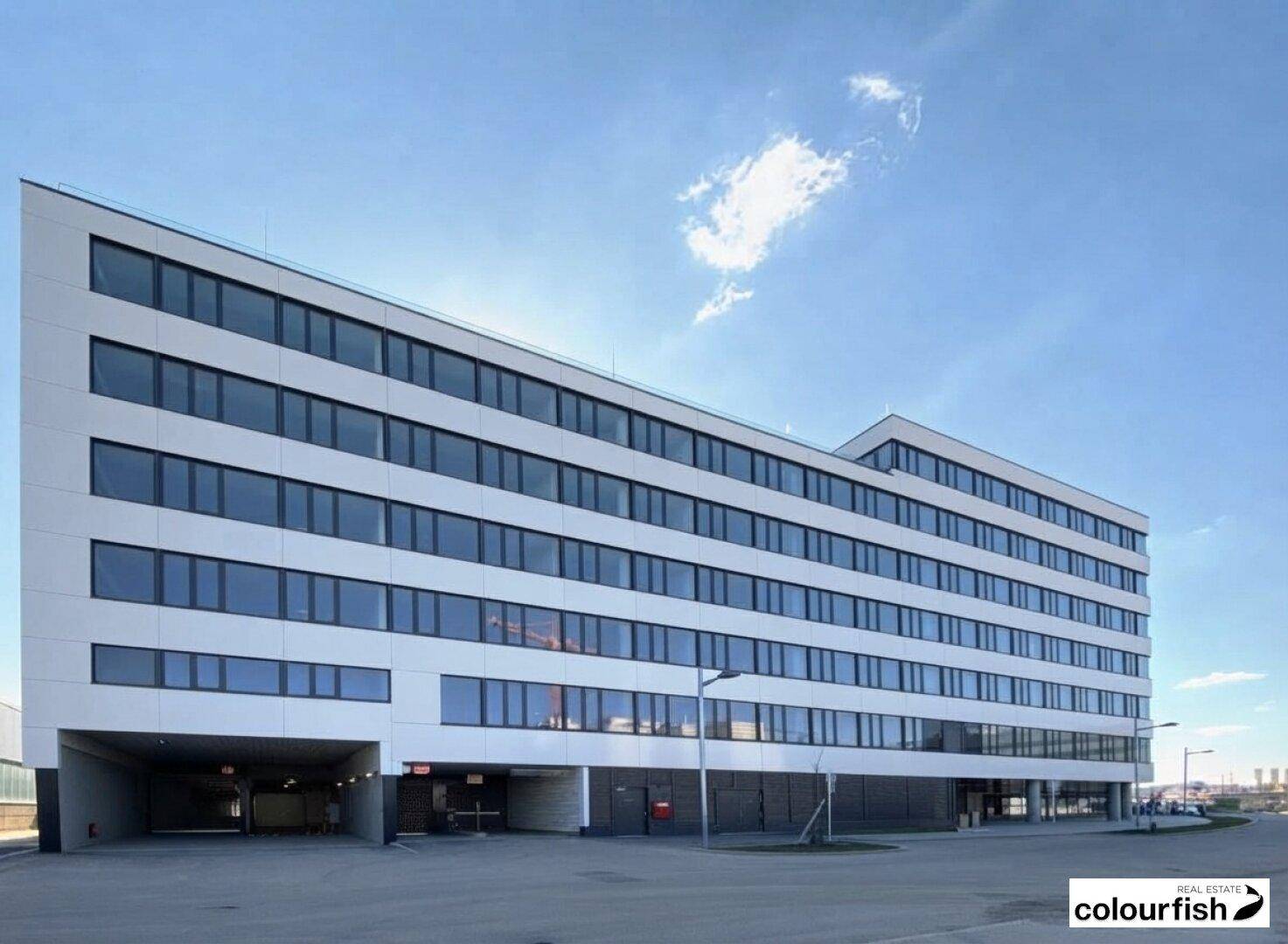 Modernes, mehrstöckiges Geschäftsgebäude mit weißer Fassade, großen Fenstern und integrierter Tiefgarage.