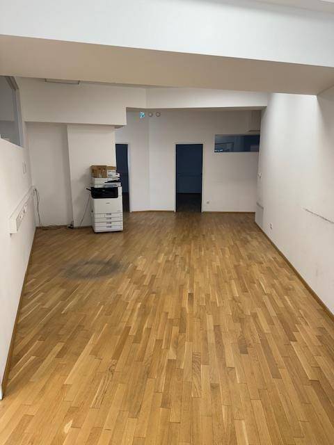 Großer offener Bürobereich mit Holzparkettboden, weißen Wänden und einem Kopiergerät.