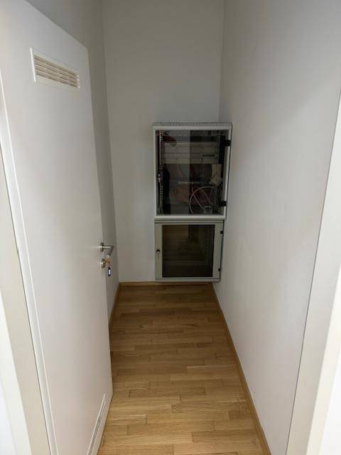 Kleiner Abstellraum mit Holzparkettboden und einem Serverschrank.