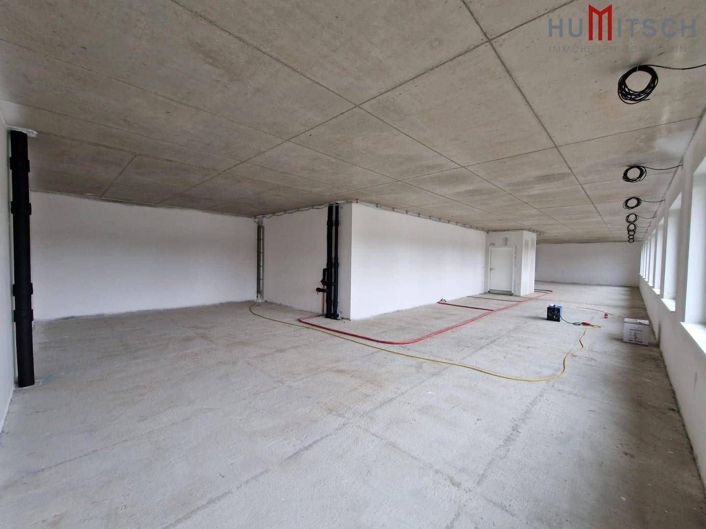 Rohbau eines großen Büroraums mit Betonboden und -decke, bereit für den Ausbau.