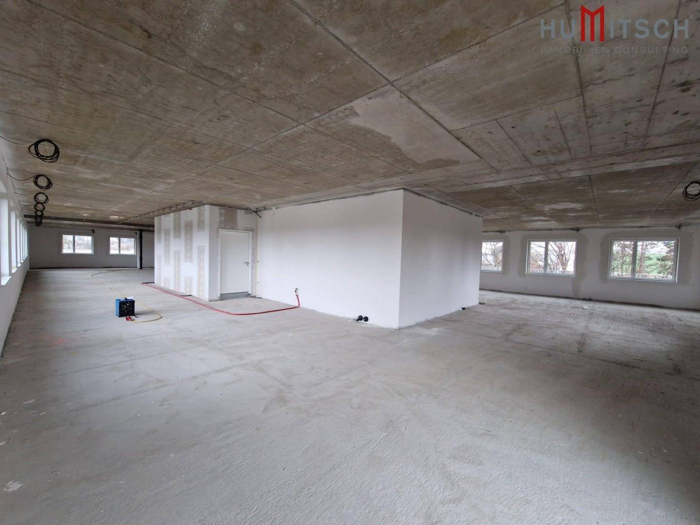 Rohbau eines Büroraums mit Betonboden und teilweise errichteten Trennwänden.
