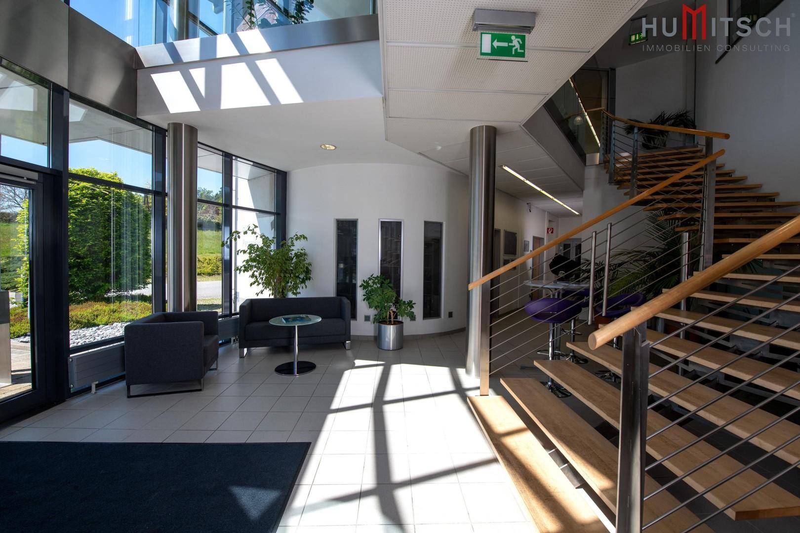 Heller Eingangsbereich mit moderner Treppe, Fliesenboden und Sitzgelegenheiten.