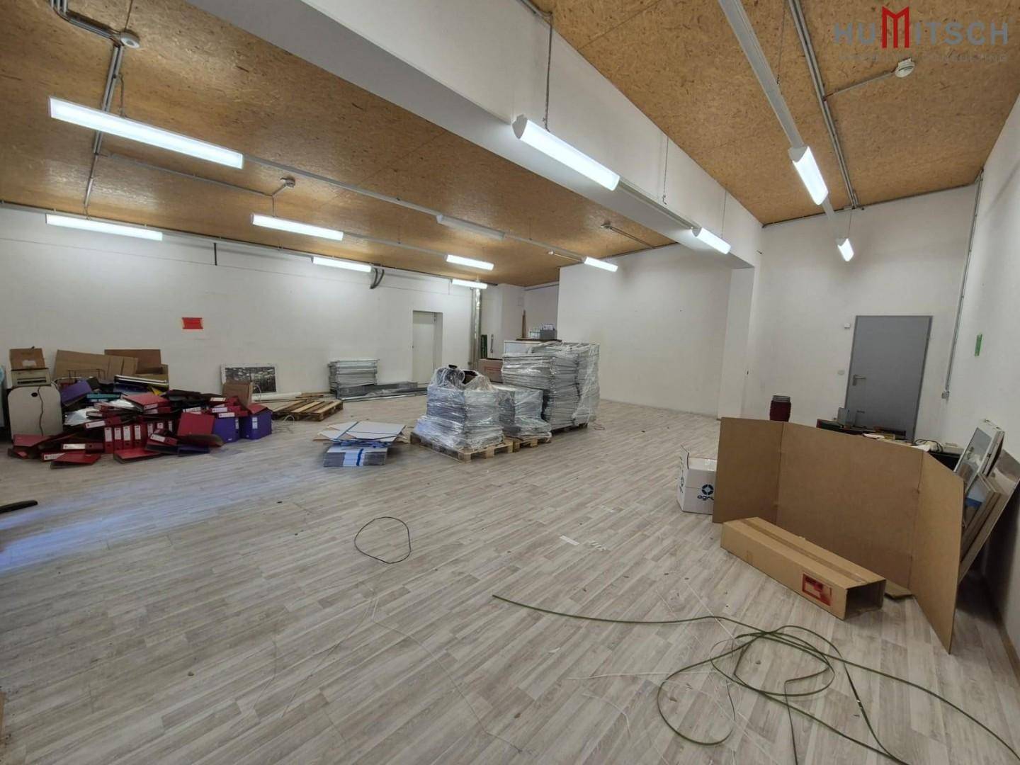 Große Lagerfläche mit Laminatboden, Leuchtstoffröhren und verschiedenen Materialien.