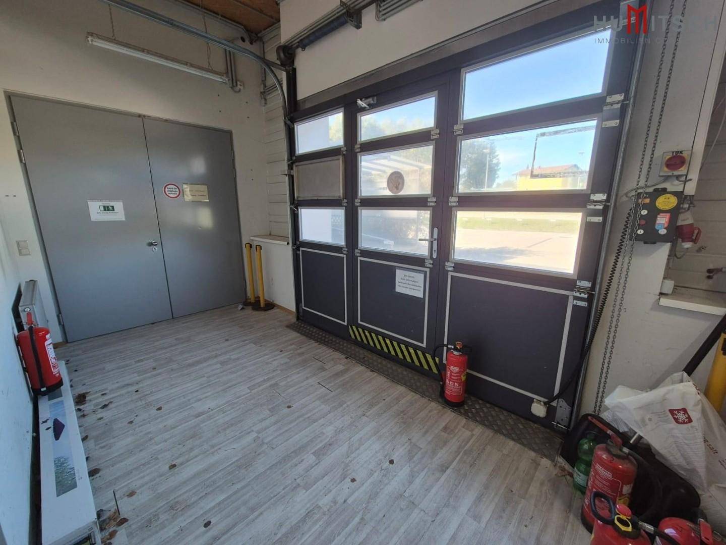 Eingangsbereich einer Lagerhalle mit Rolltor, Brandschutzmitteln und robustem Boden.