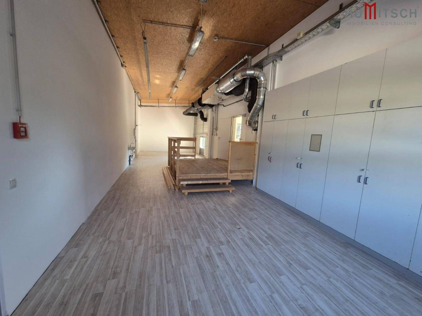 Werkstattbereich mit Holzoptik-Vinylboden, Einbauschränken und einer erhöhten Plattform.