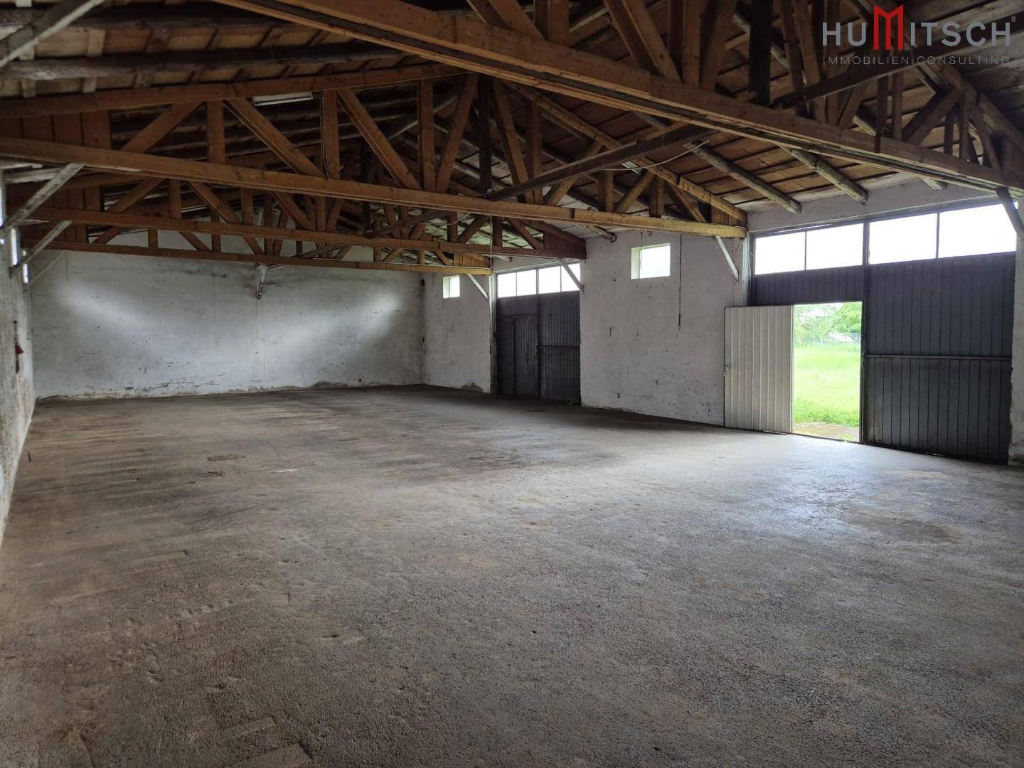 Geräumige Lagerhalle mit hohen Decken, Betonboden und großen Toren für den Zugang.