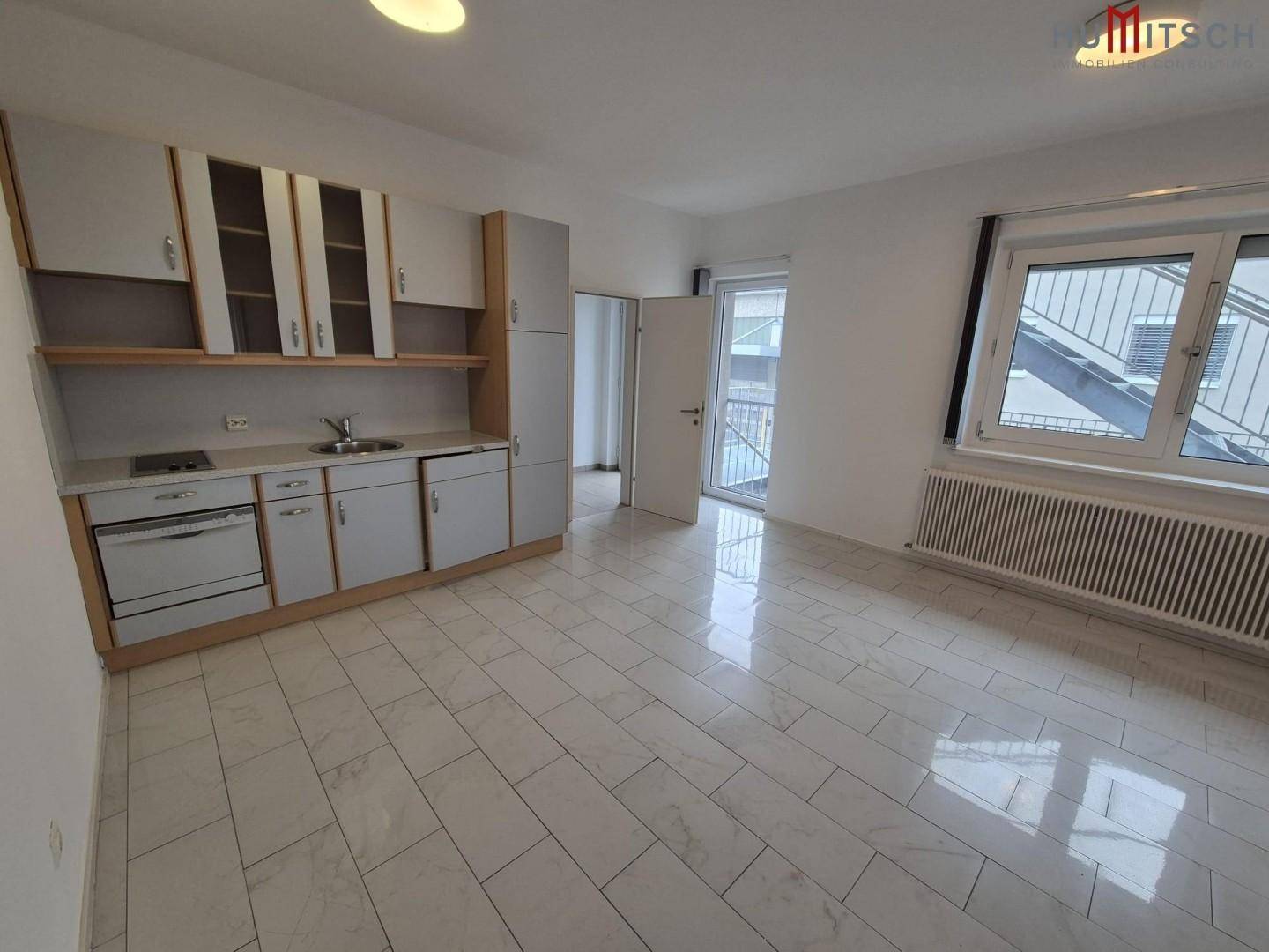 Raum mit kleiner Küchenzeile, Fliesenboden und Zugang zu einem Balkon, ideal für Pausen.