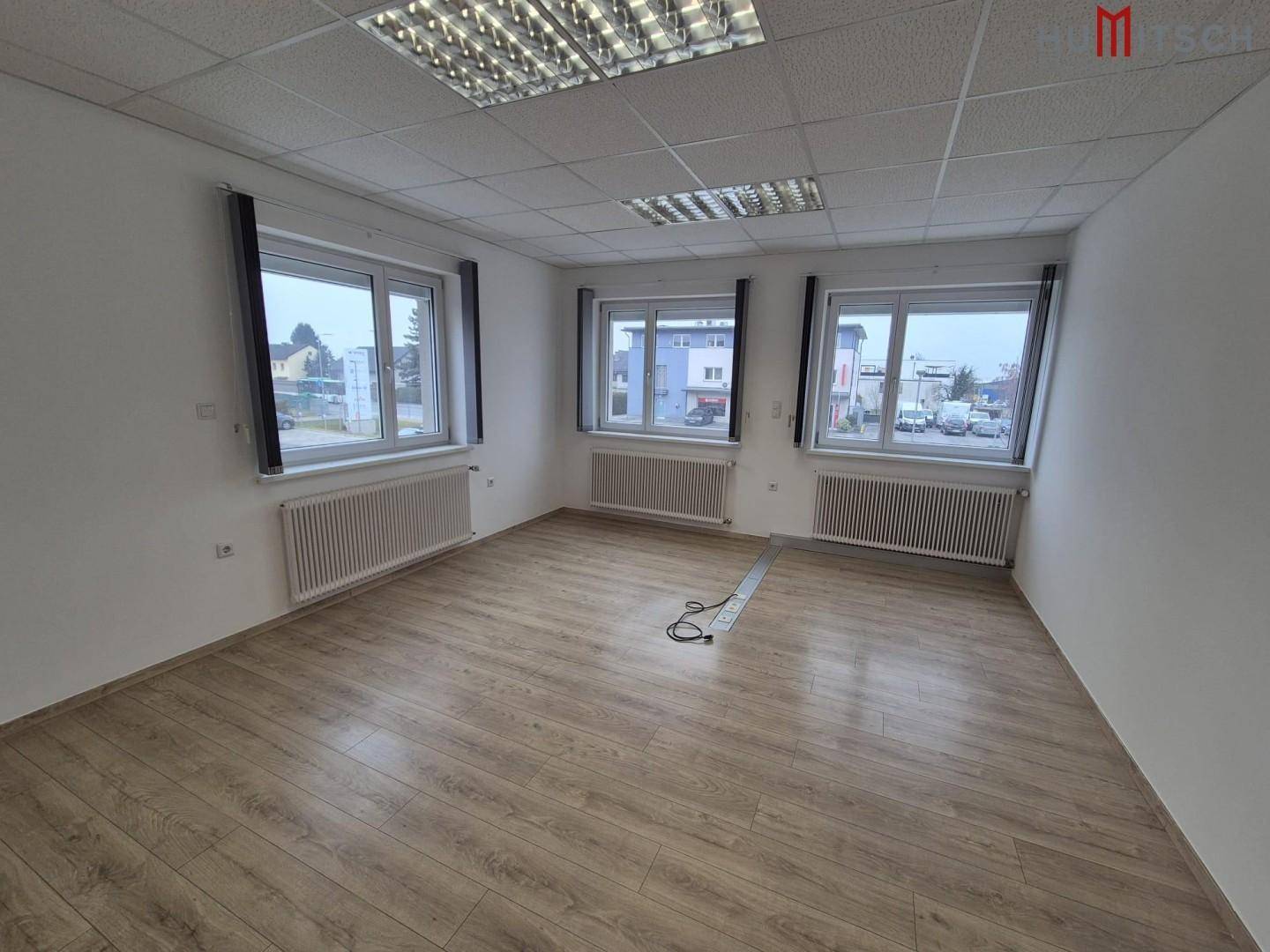 Großes Büro mit Laminatboden und vielen Fenstern, sorgt für helle und offene Arbeitsbereiche.