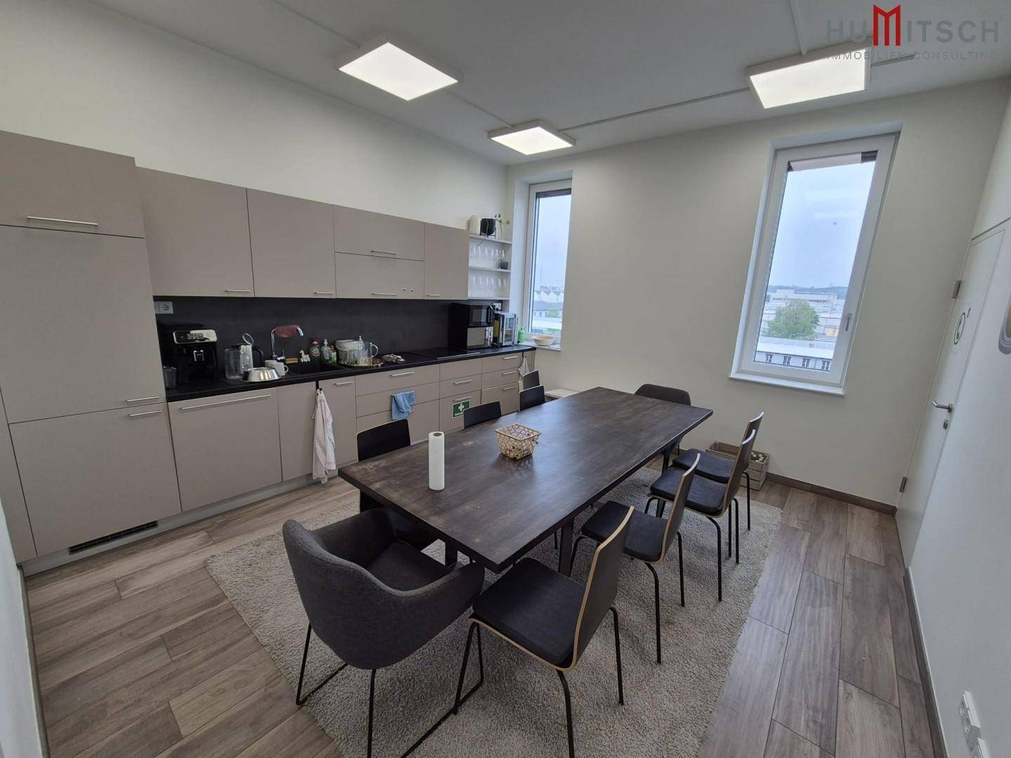 Moderne Büroküche mit Esstisch, Einbauschränken und Holzboden.