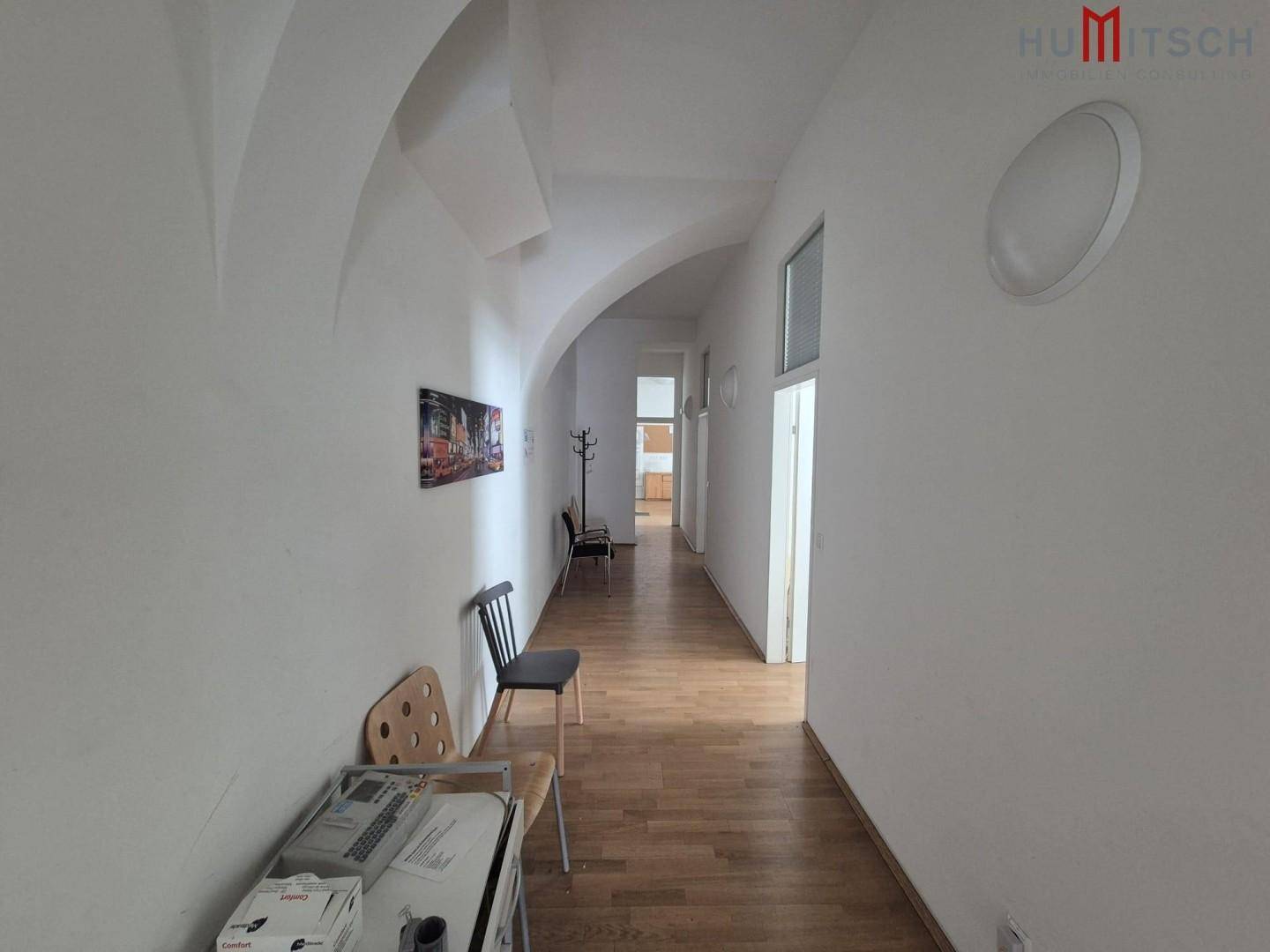 Langer Flur mit Holzboden und gewölbter Decke, führt zu weiteren Räumen der Immobilie.