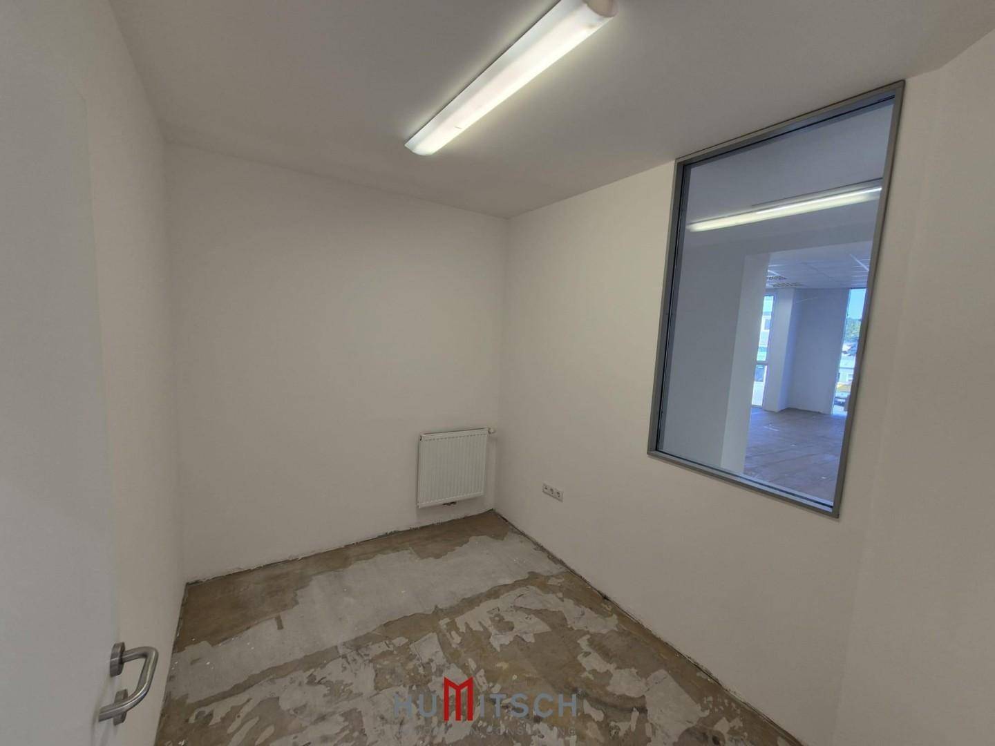 Kompakter Raum mit einer internen Fensteröffnung und unfertigem Boden, geeignet für verschiedene Bürozwecke.