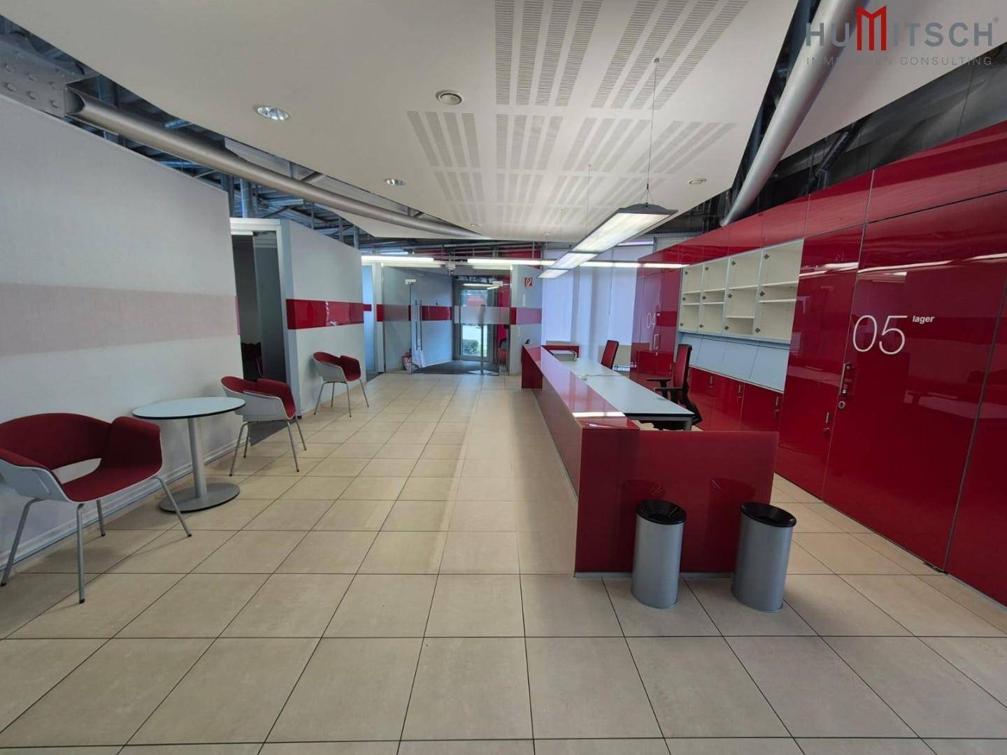 Moderner Empfangsbereich mit roten Akzenten, Fliesenboden und abgehängter Decke.
