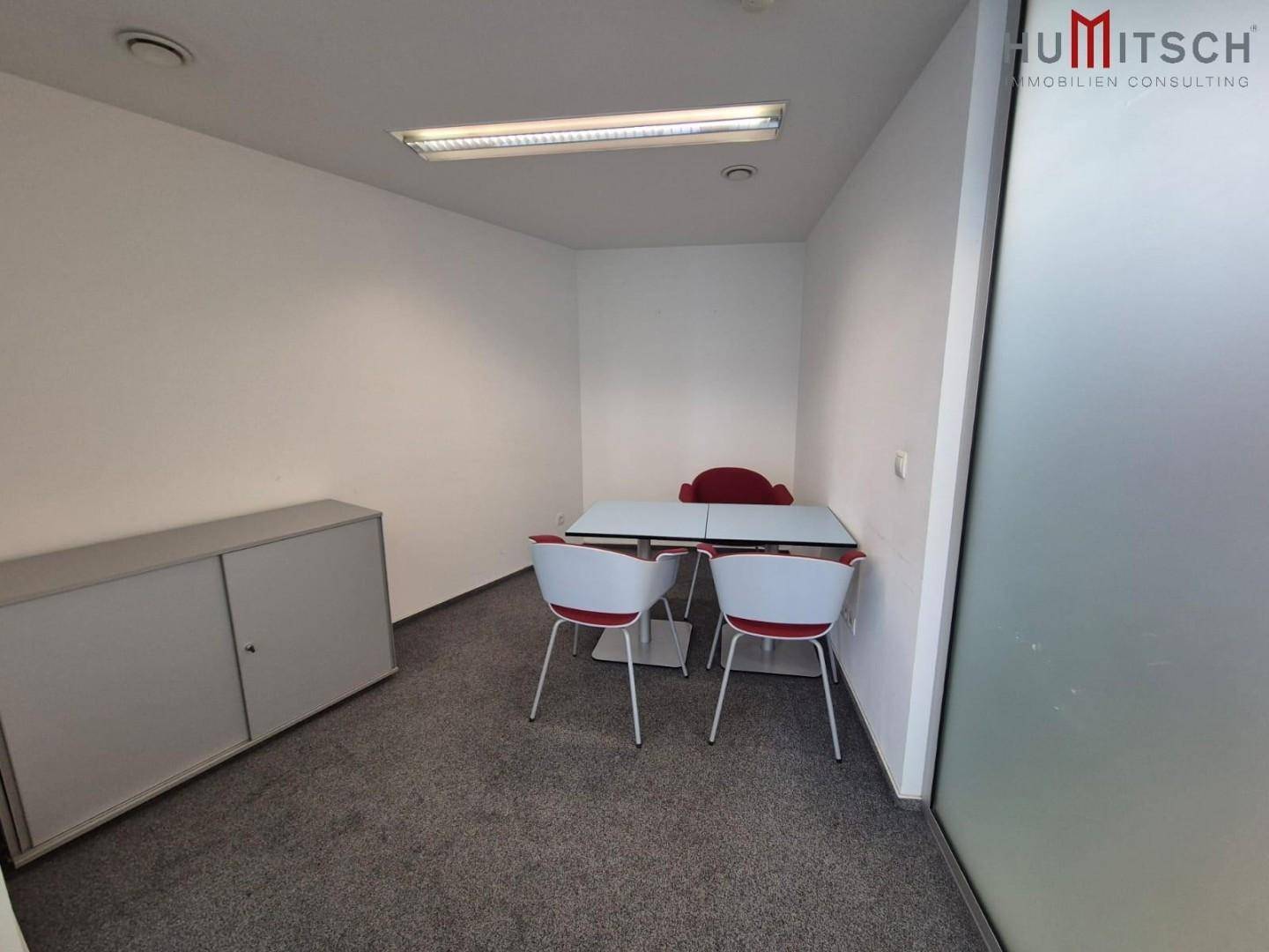 Kleiner Besprechungsraum oder privates Büro mit Teppichboden, einem Tisch und Stühlen für vertrauliche Gespräche.