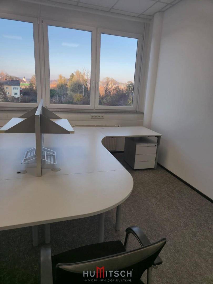 Detailansicht eines Büros mit Schreibtisch, Bürostuhl und Blick aus dem Fenster auf die Umgebung.