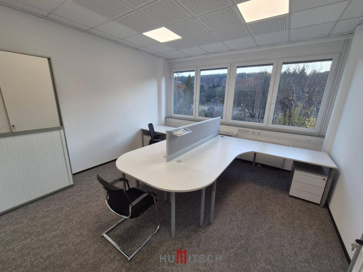 Büro mit Teppichboden, zwei Arbeitsplätzen und einem Schrank, bereit für neue Mieter.