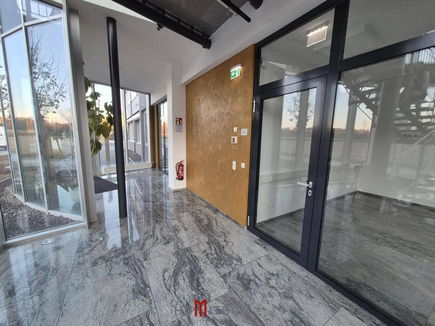 Moderner Eingangsbereich mit Granitboden, großen Glasfronten und einer dekorativen Wand.