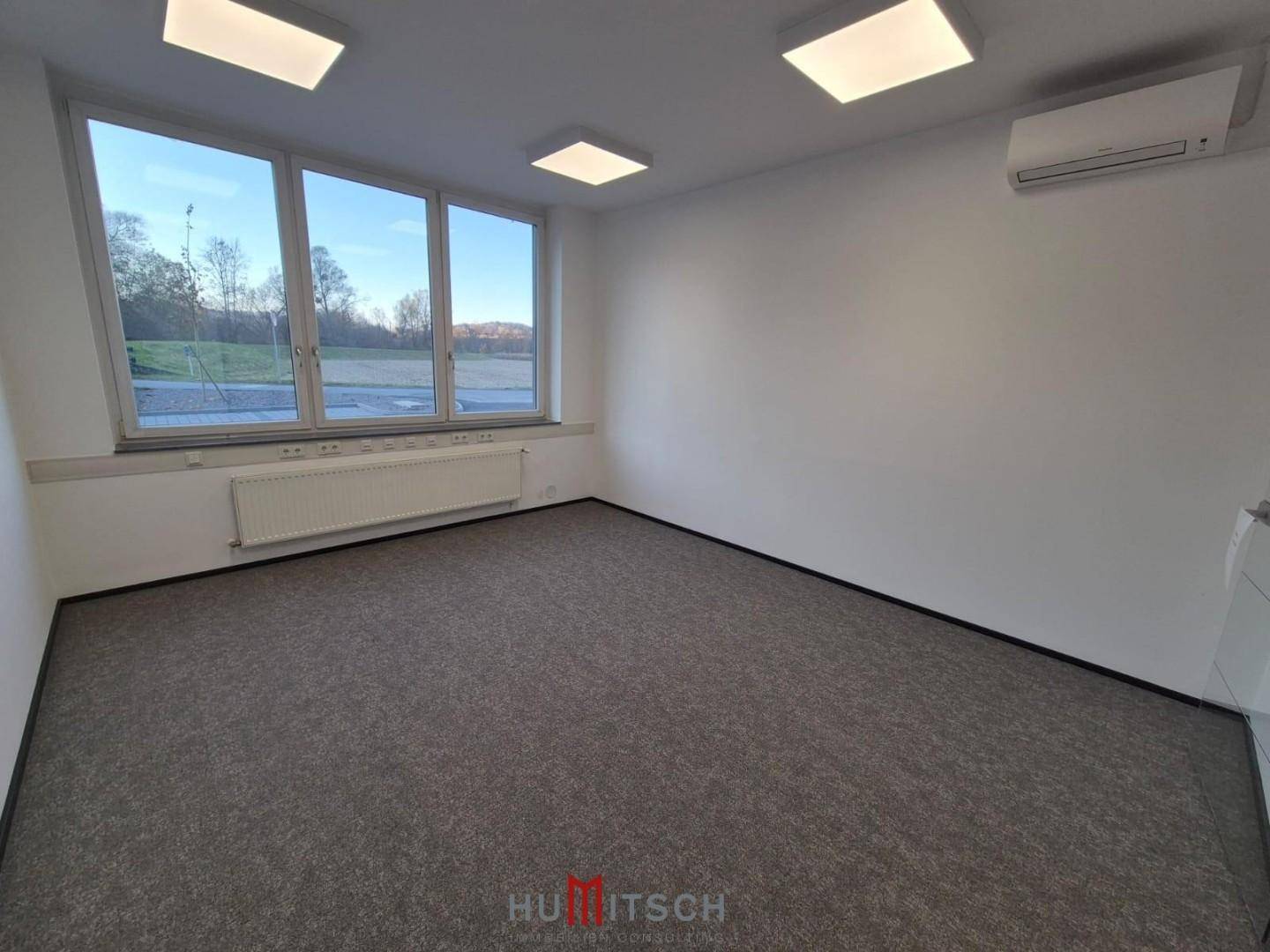 Helles Büro mit Teppichboden, großen Fenstern und Klimaanlage, bietet einen weiten Ausblick.